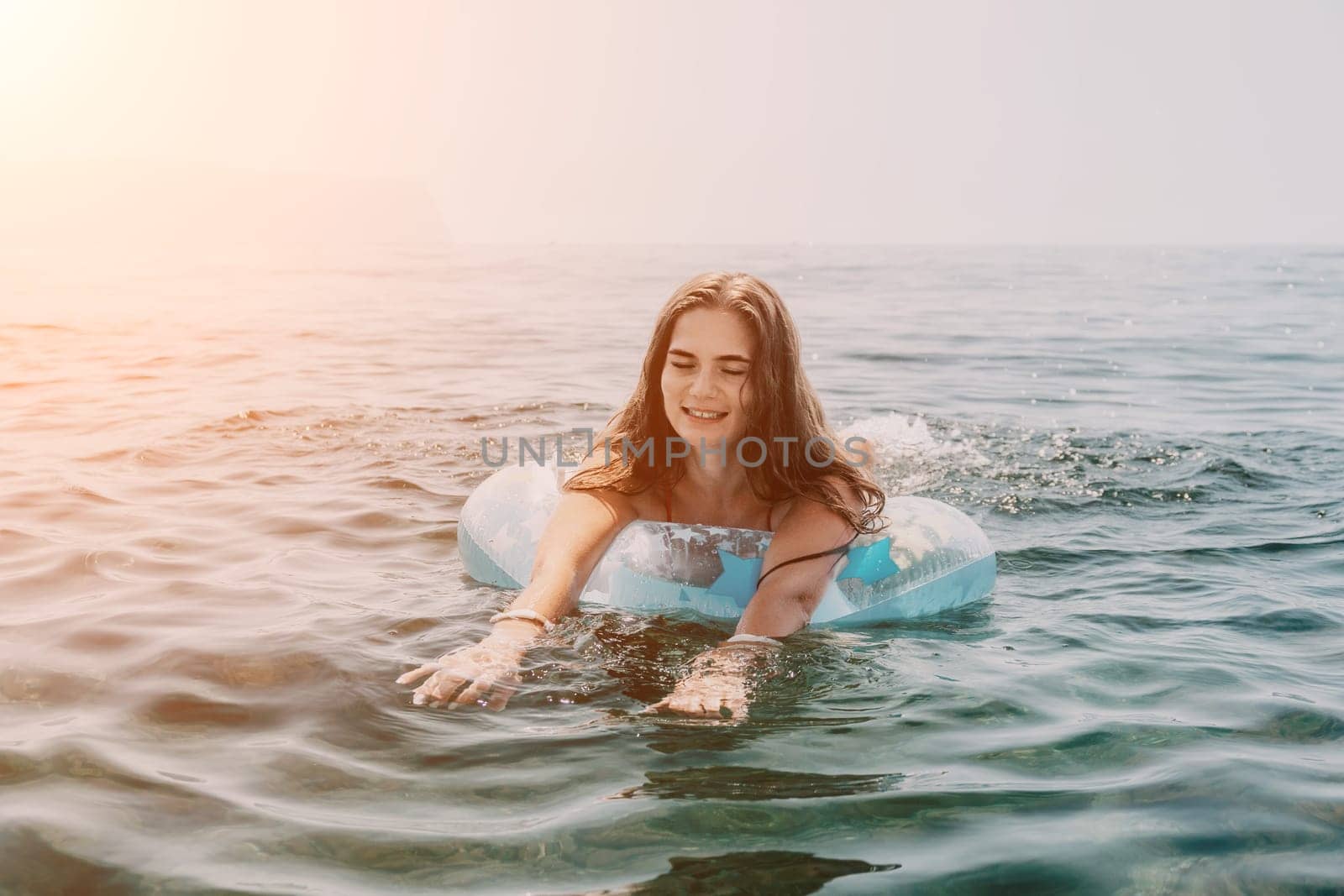 Woman summer sea. Happy woman swimming with inflatable donut on the beach in summer sunny day, surrounded by volcanic mountains. Summer vacation concept. by panophotograph