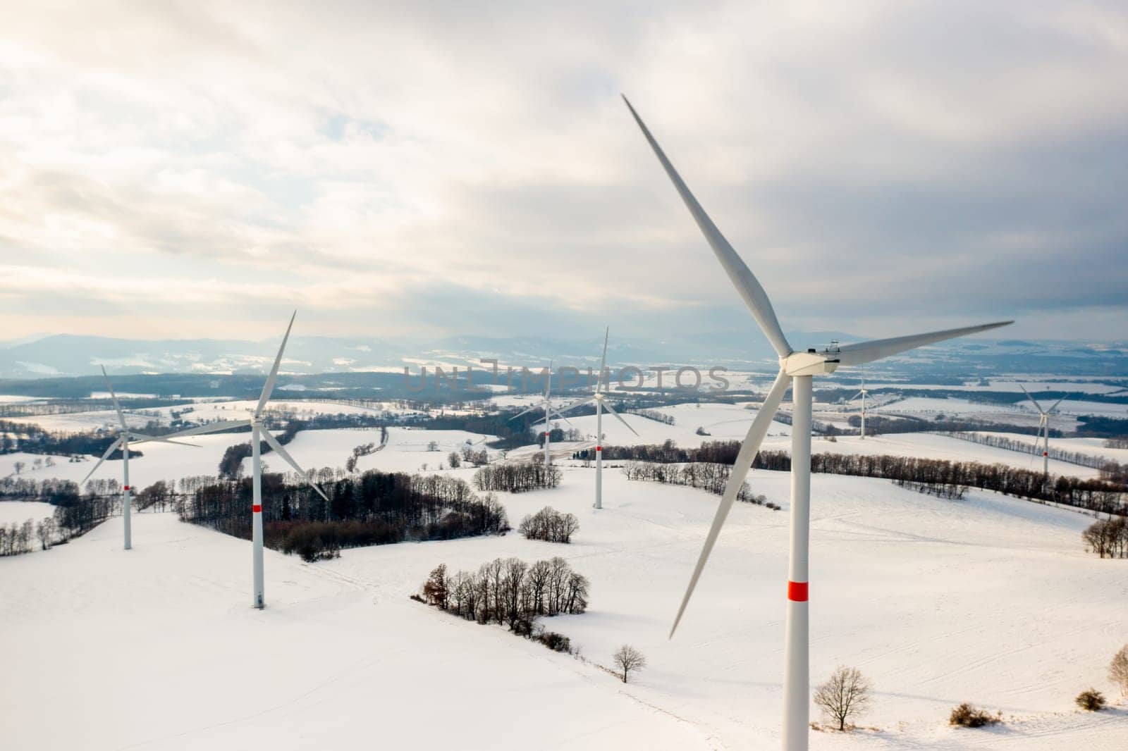 Panoramic view of wind turbines or windmills for production of a clean and renewable energy source in winter.