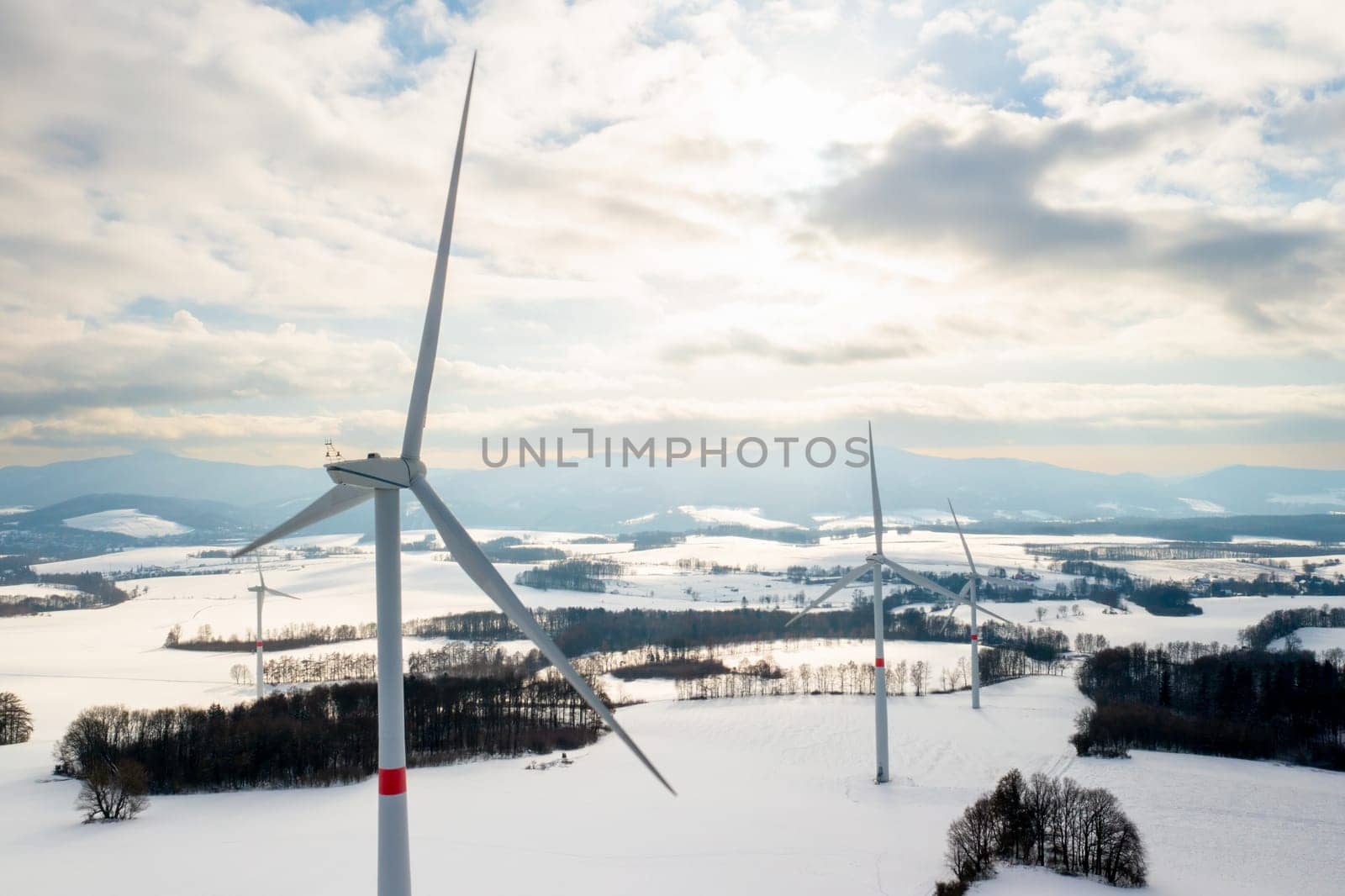 Panoramic view of wind turbines in a field in winter at sundown. Green energy producing concept