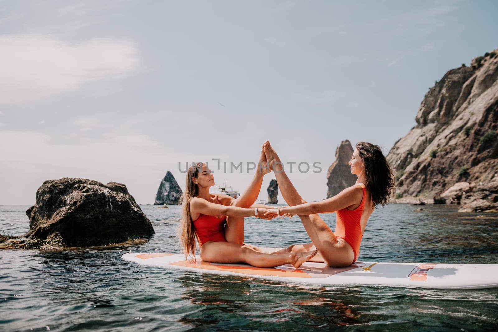 Woman sup yoga. Middle age sporty woman practising yoga pilates on paddle sup surfboard. Female stretching doing workout on sea water. Modern individual hipster outdoor summer sport activity