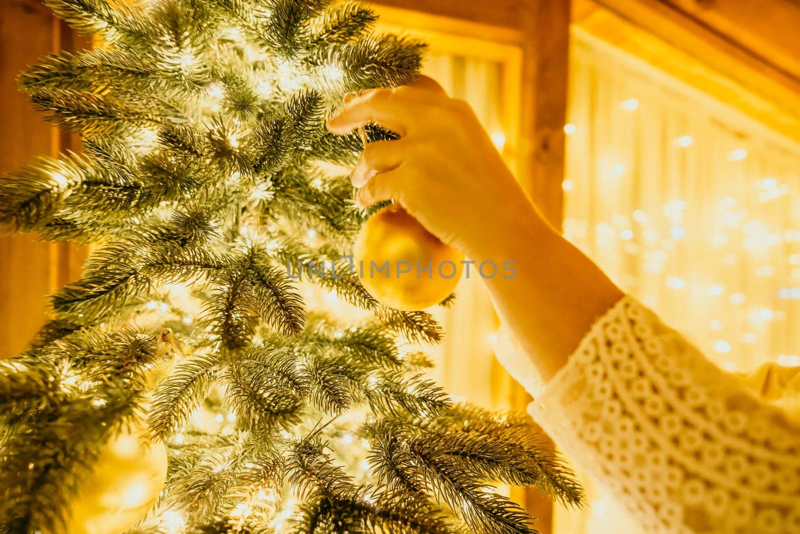 A Christmas tree with gold ornaments and lights. The tree is decorated with gold balls and is lit up with lights.