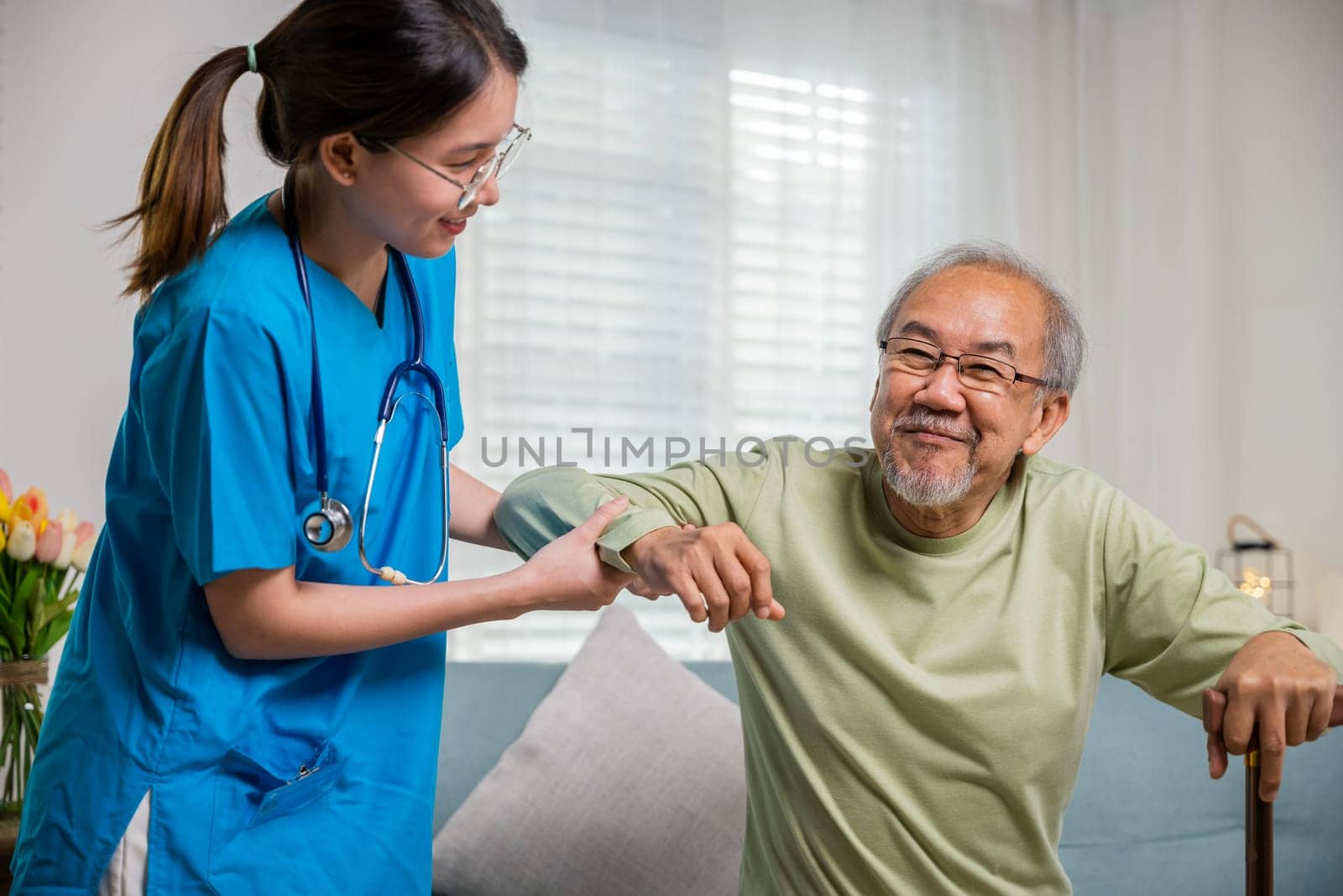 Caring nurse helping supporting senior disabled man to stand up with walking stick by Sorapop
