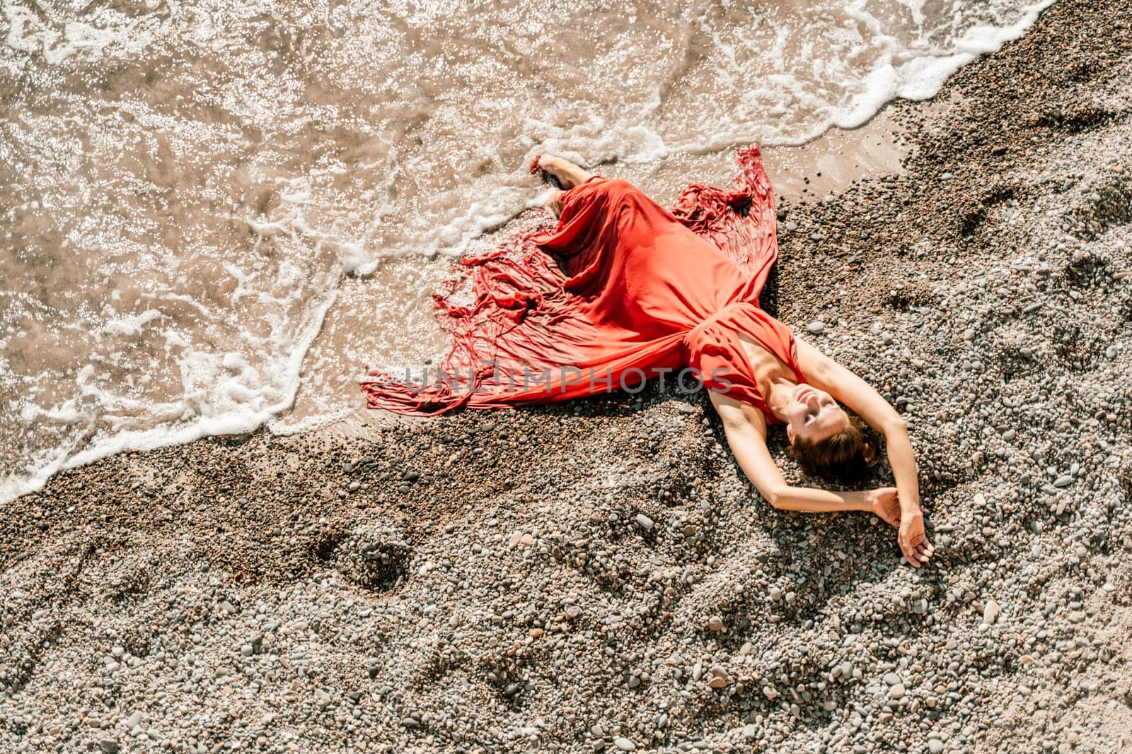 Woman red dress sea. Female dancer in a long red dress posing on a beach with rocks on sunny day by Matiunina