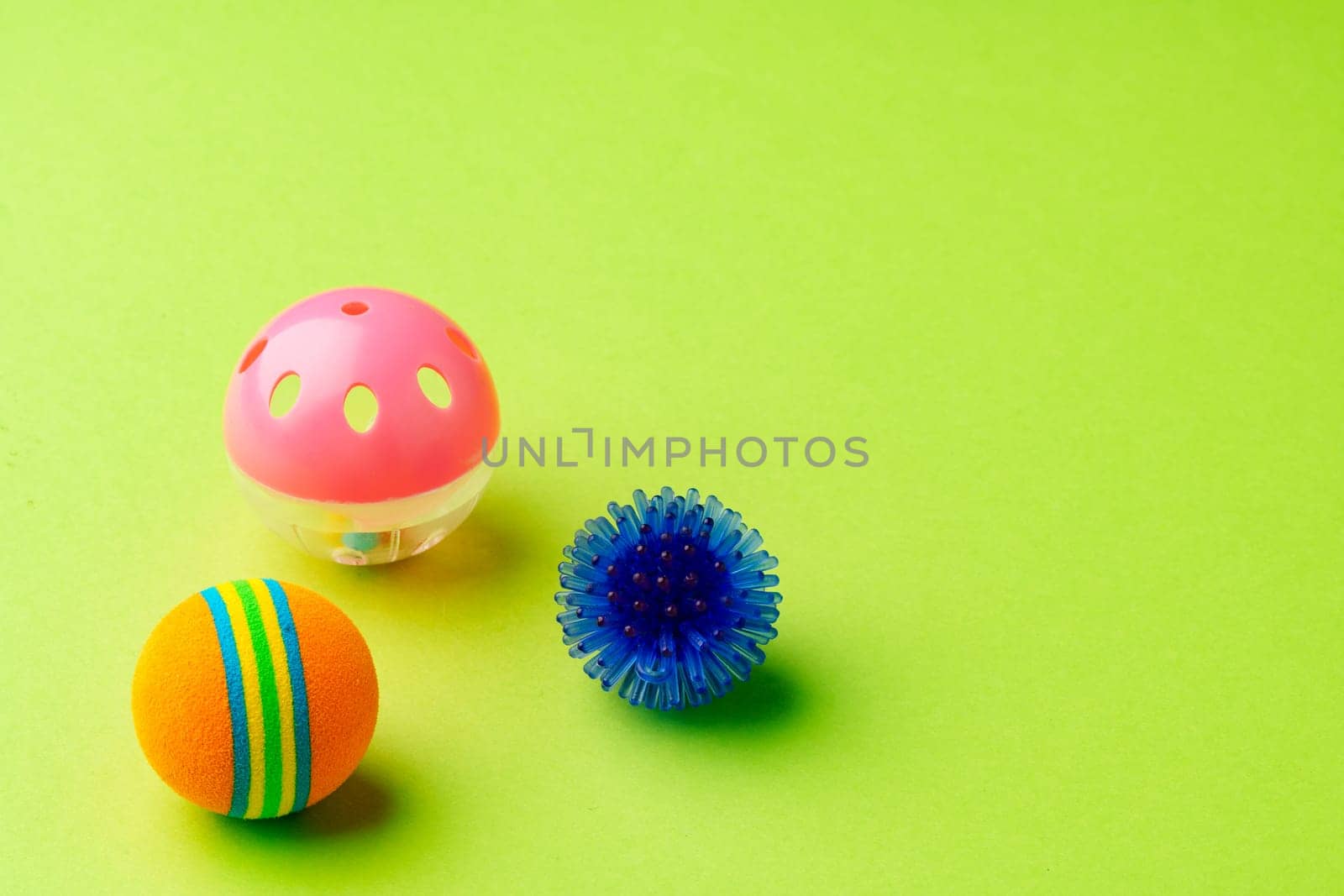 Colorful pet toys balls on green background close up