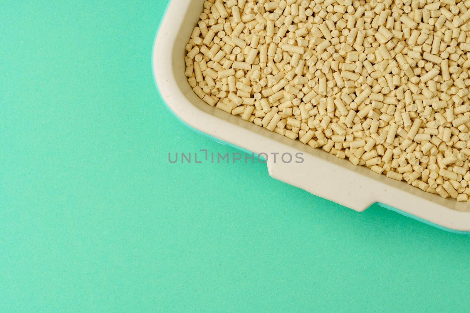 Pet litter box with bio filler on green background close up