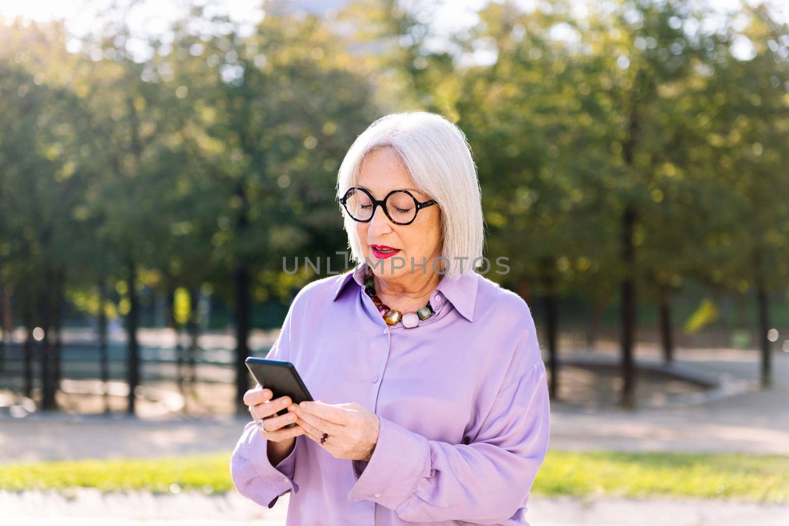 senior woman using mobile phone outdoors, concept of technology and elderly people leisure