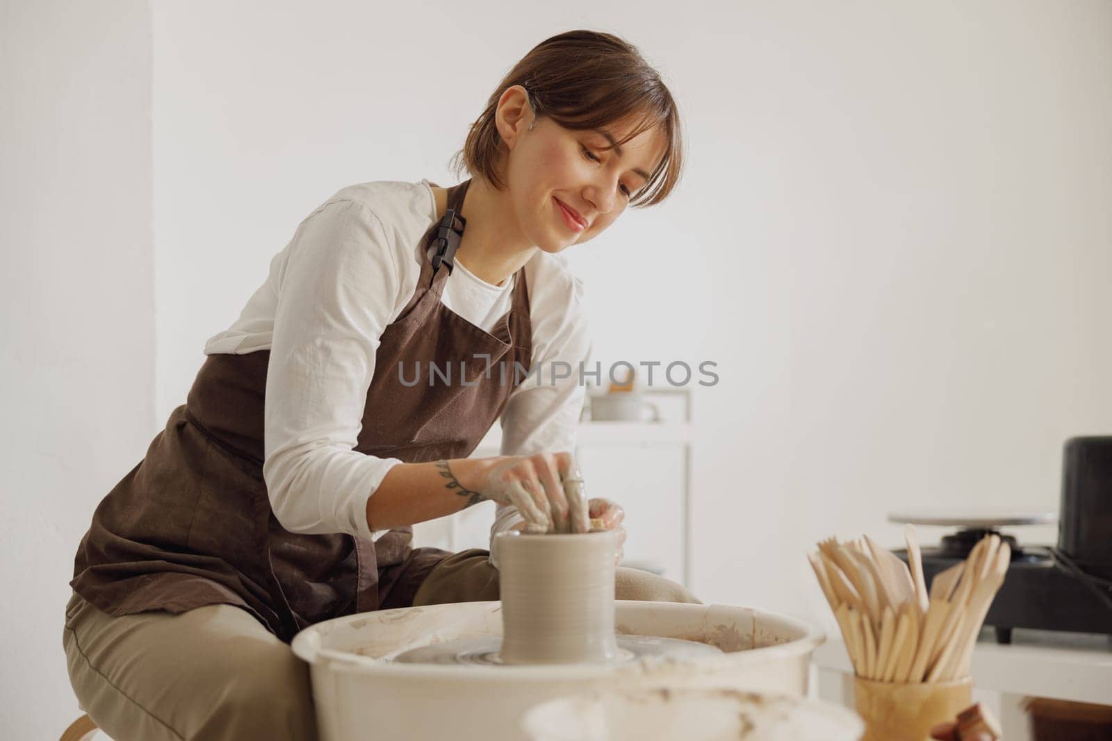 Professional female artisan shaping clay bowl in pottery studio. Ceramics art concept