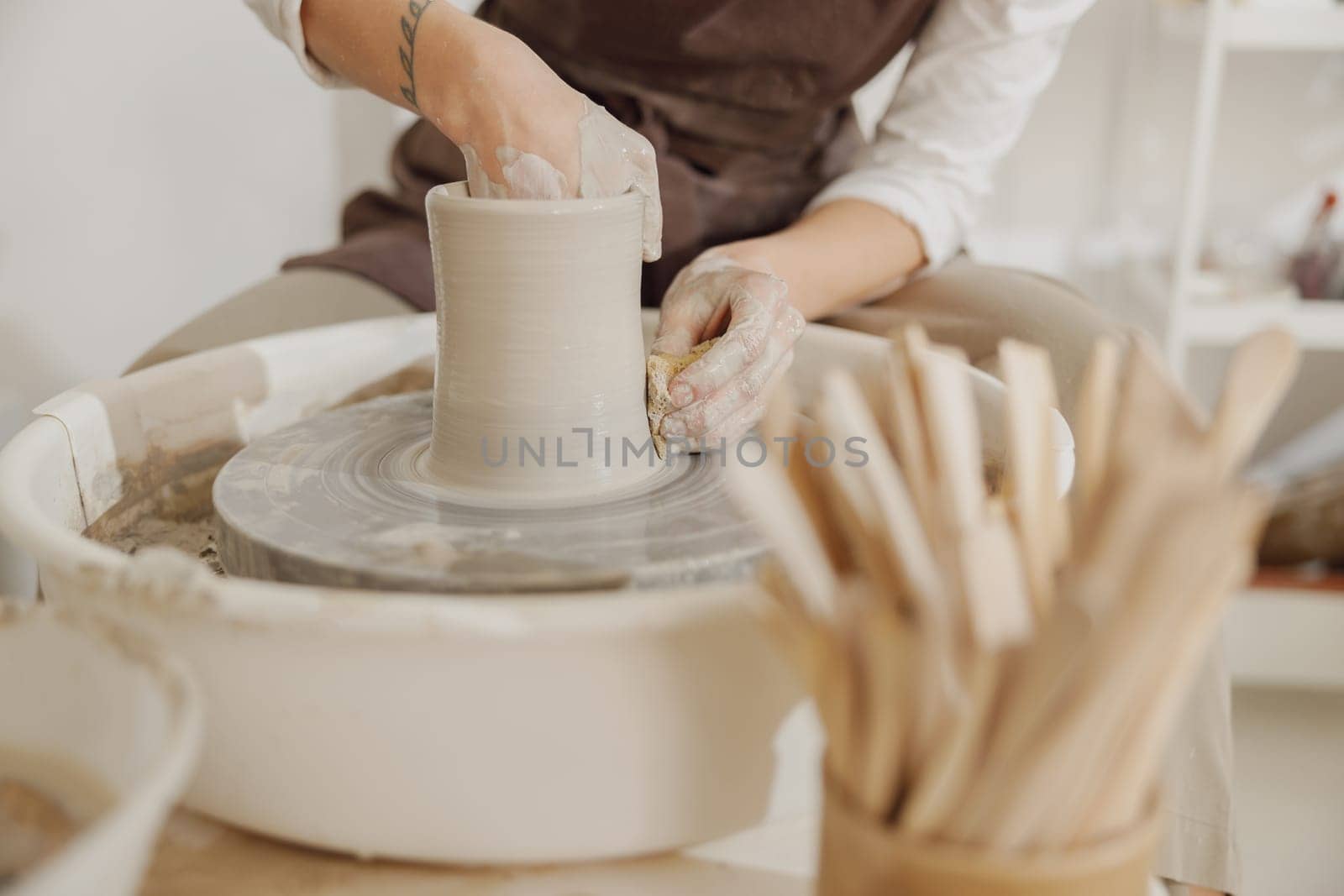 Close up of hands of professional potter molding pot shape on pottery wheel. Ceramics art concept by Yaroslav_astakhov