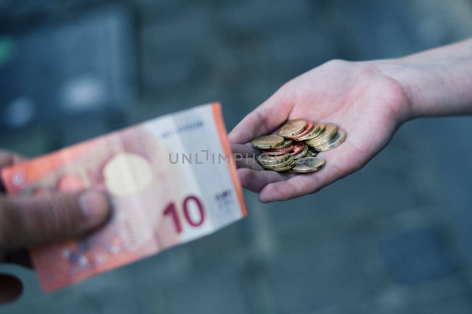 Close-up of hand giving coins to another hand with banknotes