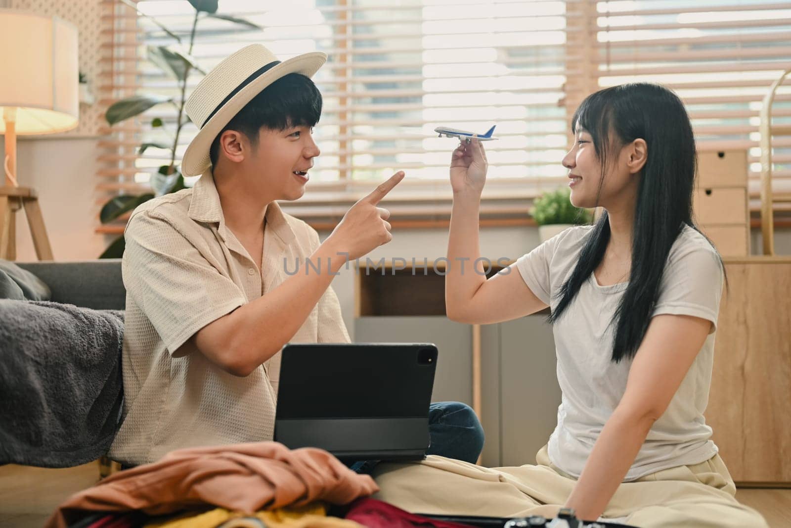 Happy Asian couple holding airplane model. Traveling, vacation and transportation concept.