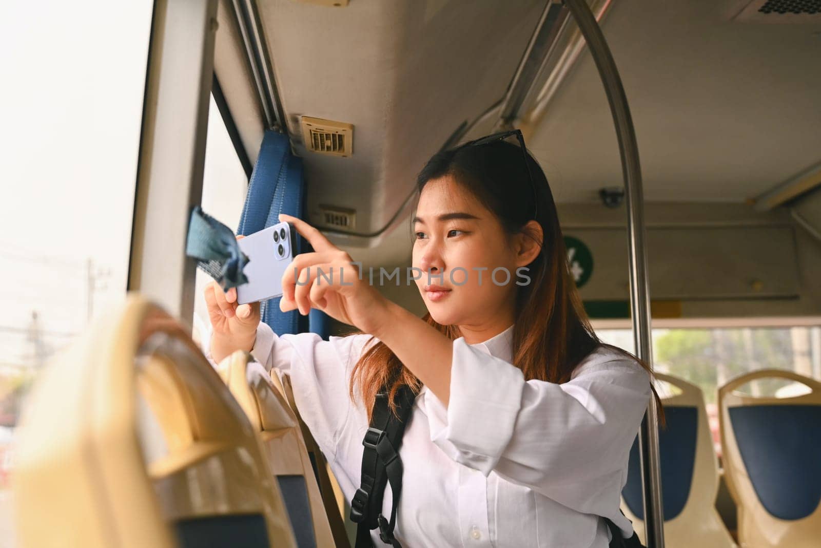 Young female tourist taking photos trough the window with smartphone.Travel lifestyle and transportation concept by prathanchorruangsak