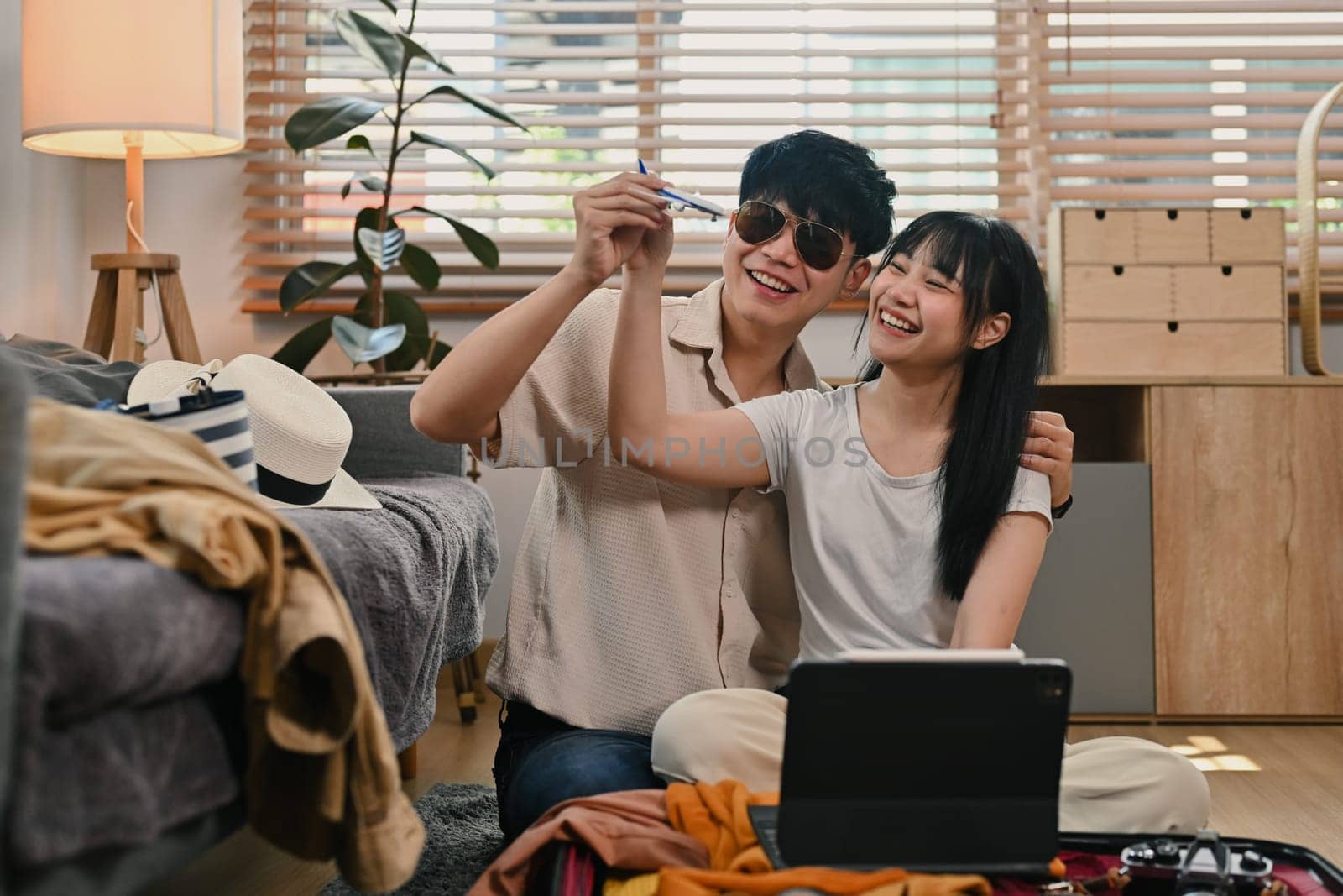 Cheerful Asian couple holding airplane model ready for vacation. Traveling, vacation and transportation concept.