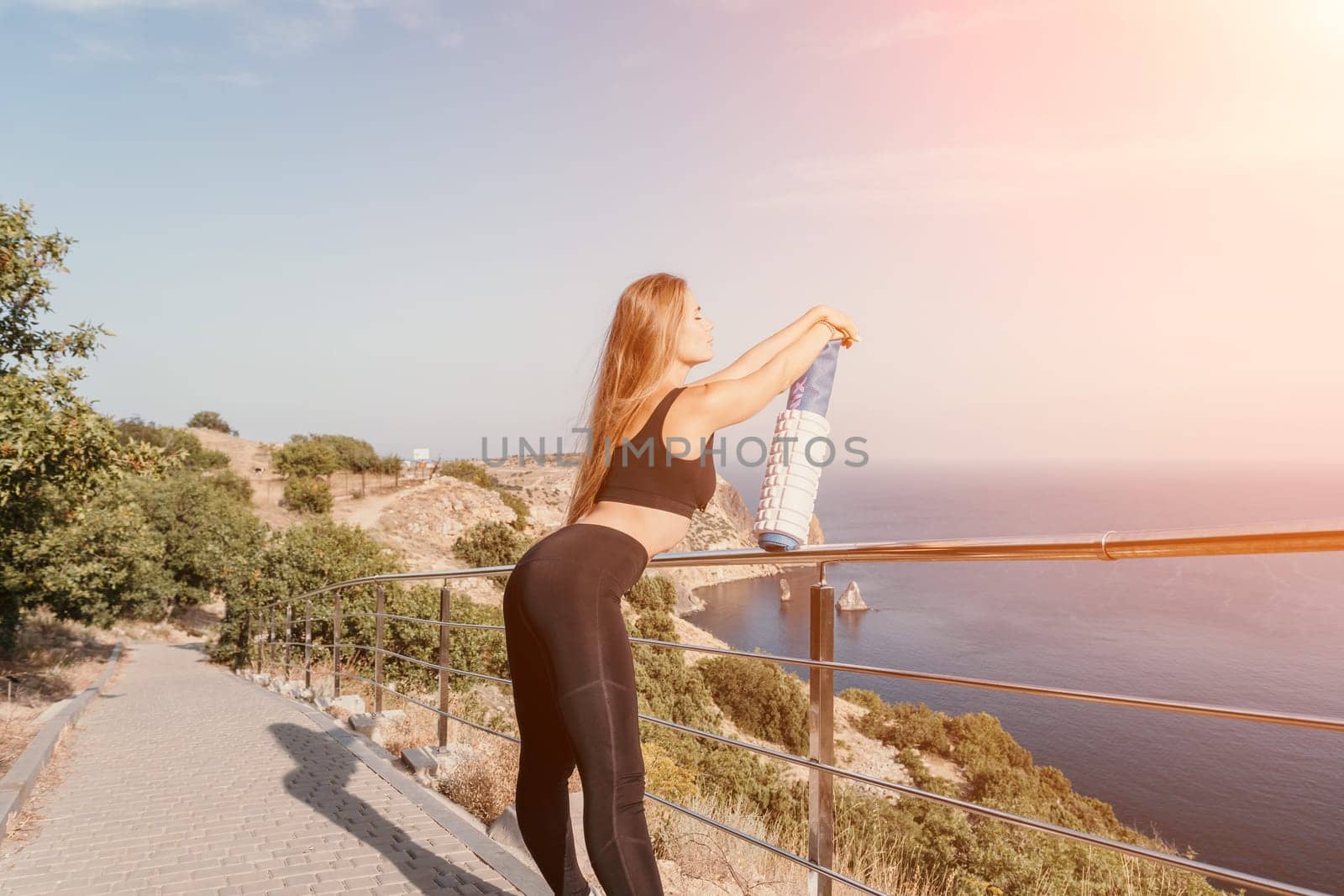 Fitness woman sea. Outdoor workout on yoga mat in park near to ocean beach. Female fitness pilates yoga routine concept. Healthy lifestyle. Happy fit woman exercising with rubber band in park.