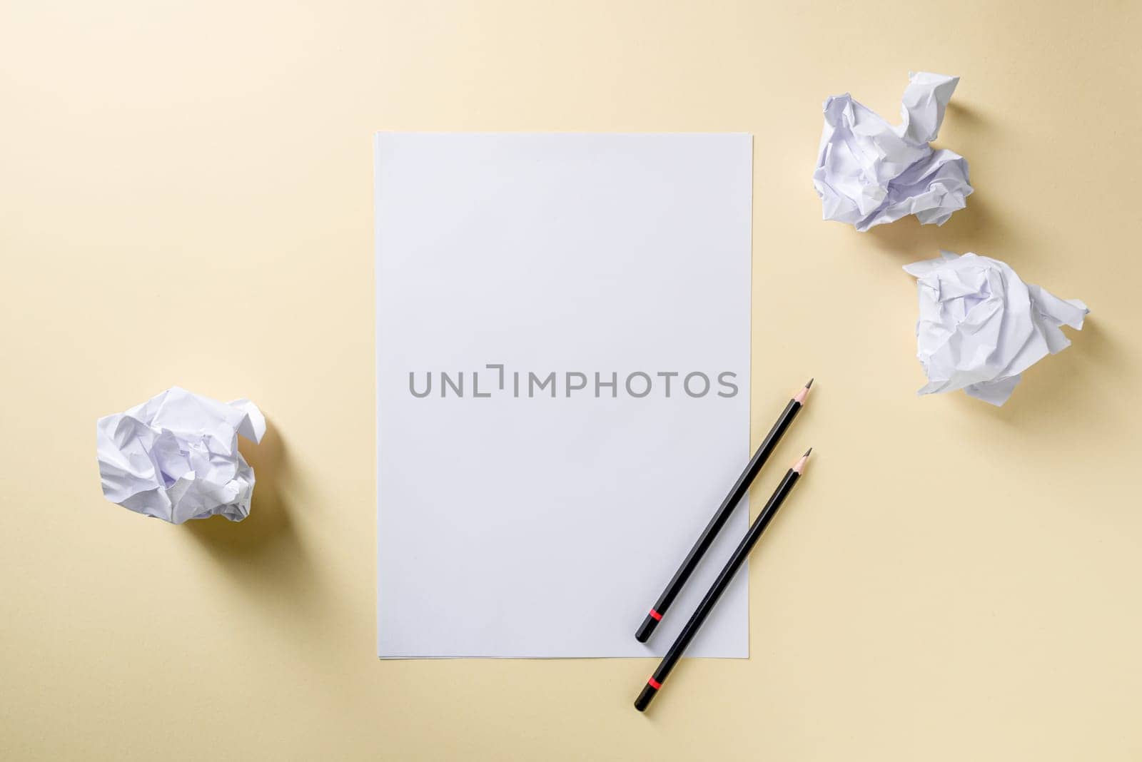 Blank writing sheet with pen and crumpled paper balls lay flat on yellow background by Sonat