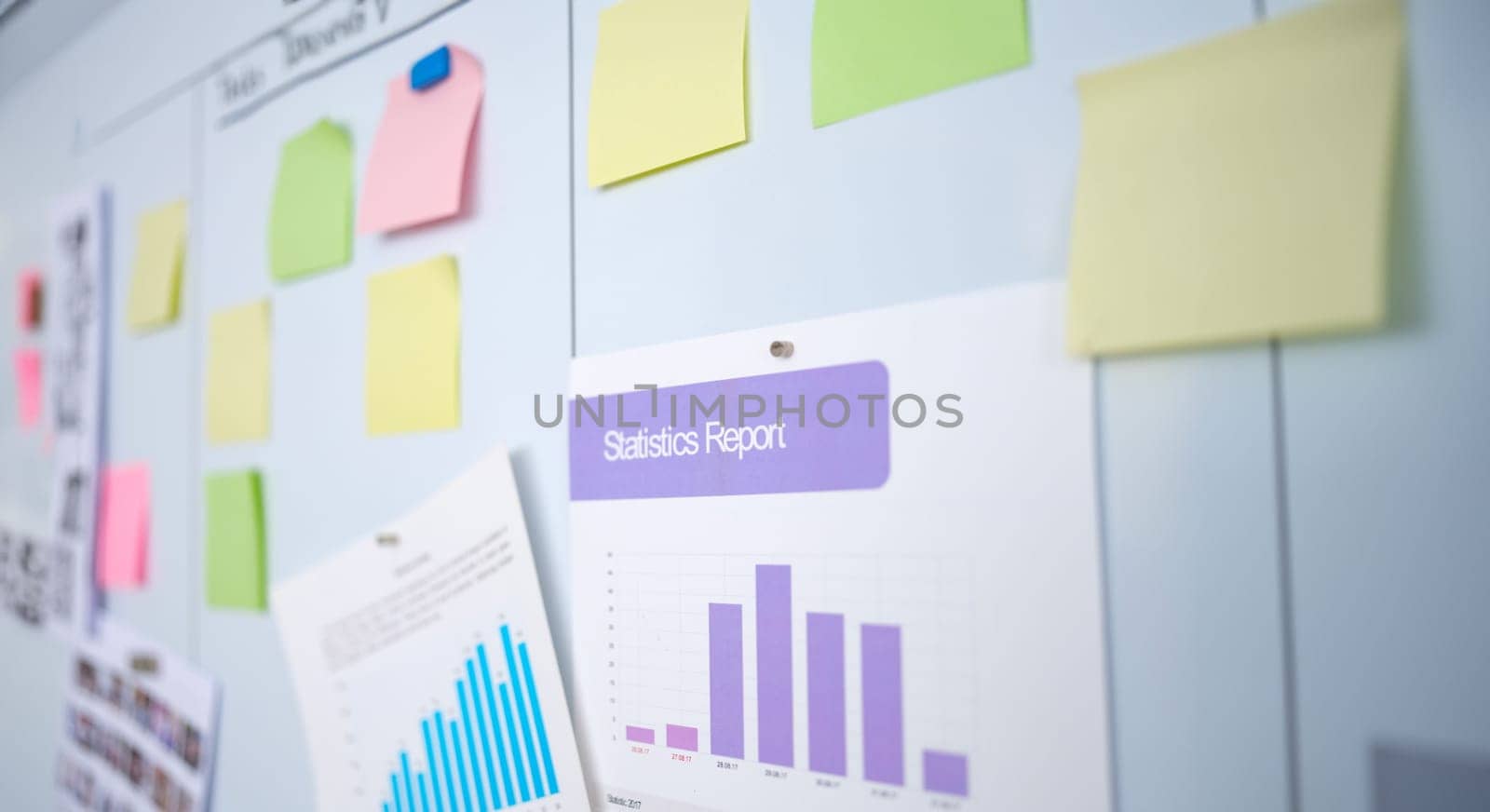 Documents with graphs of statistical reports and colorful stickers hanging on chalkboard in educational business center closeup. Business education concept