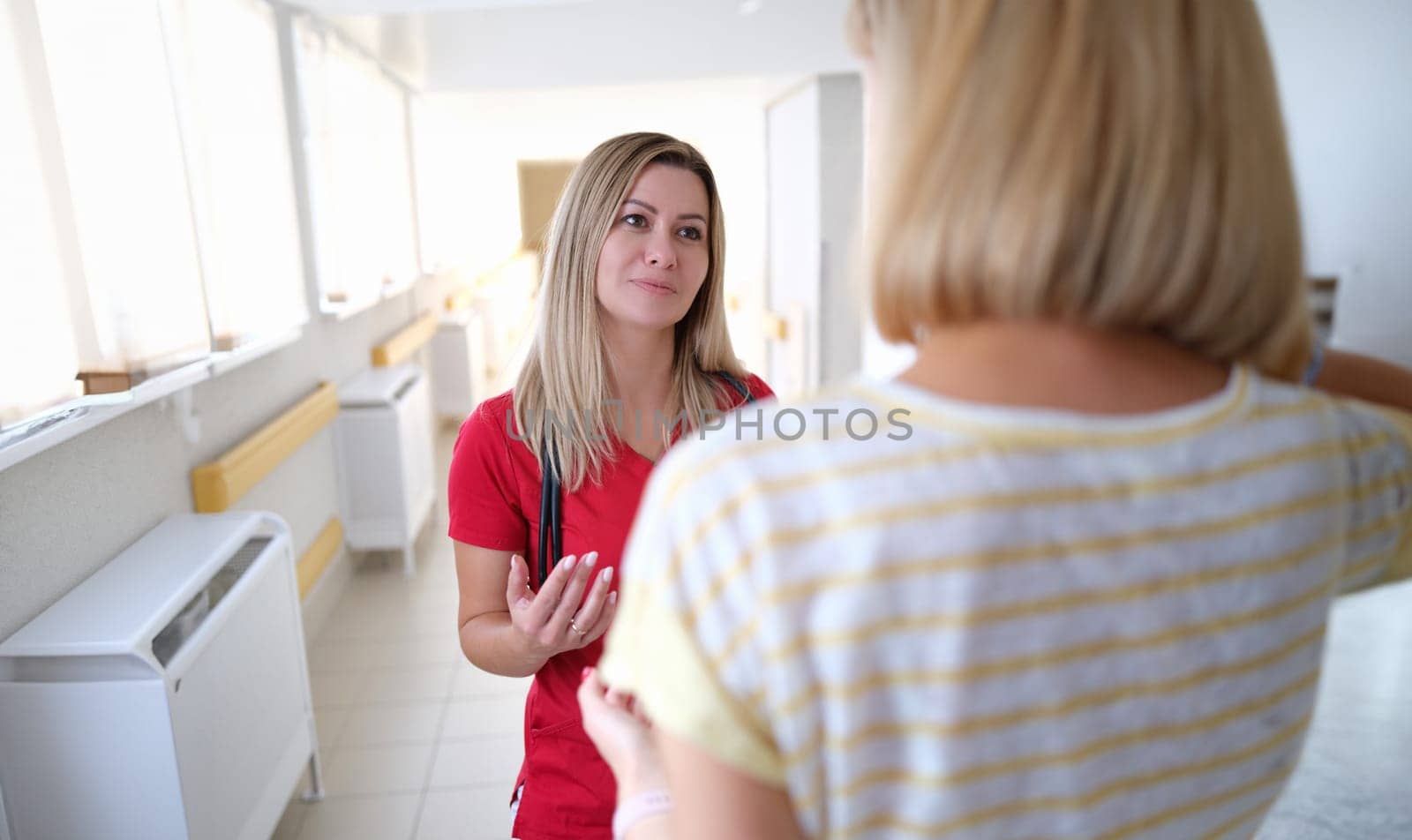 Young female doctor communicating with patient in clinic by kuprevich
