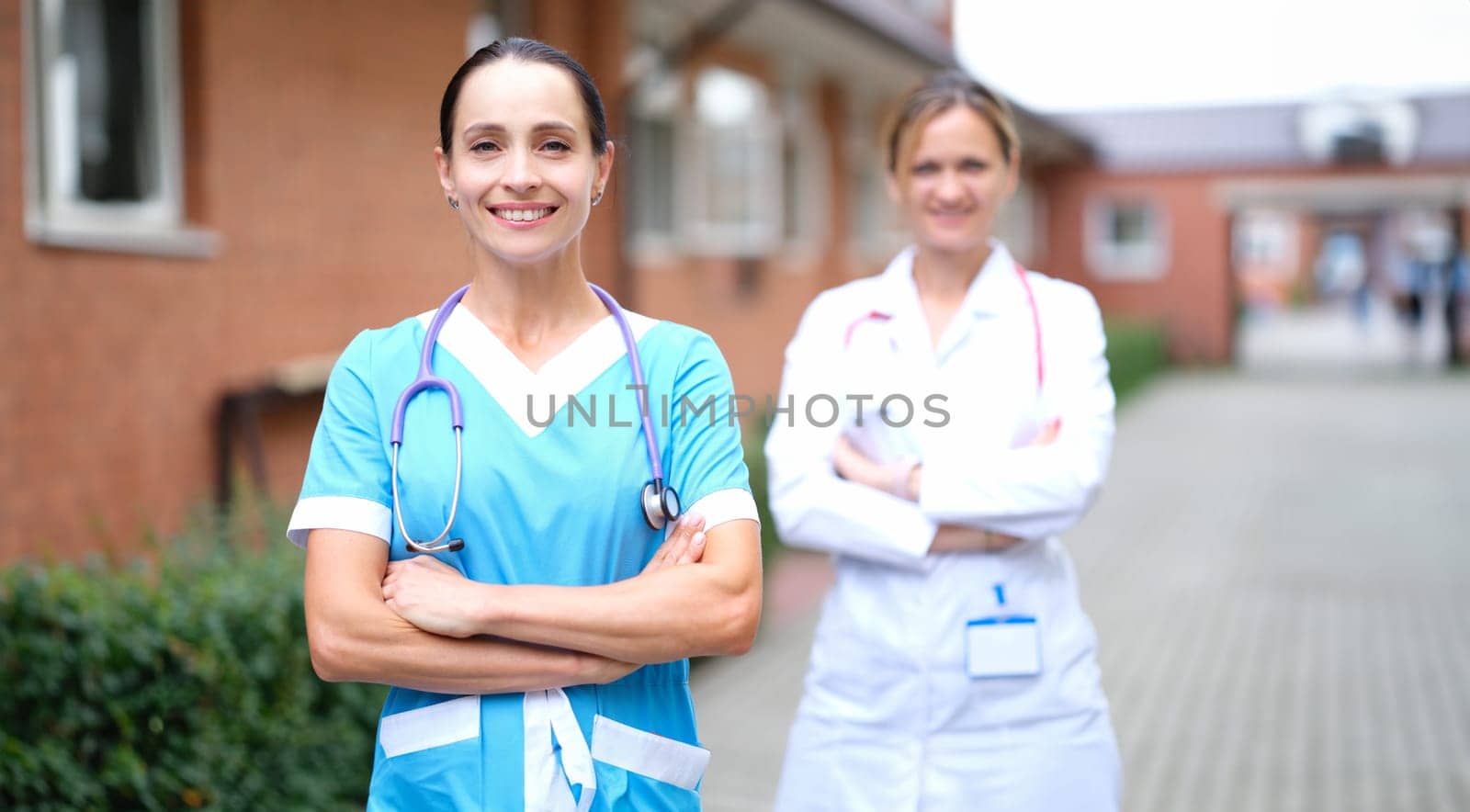 Female doctors in uniforms standing near clinic. Health insurance concept