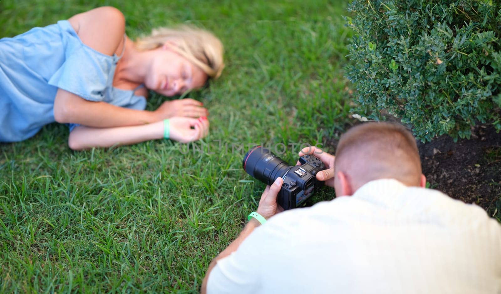 Man photographing young woman sleeping on grass by kuprevich