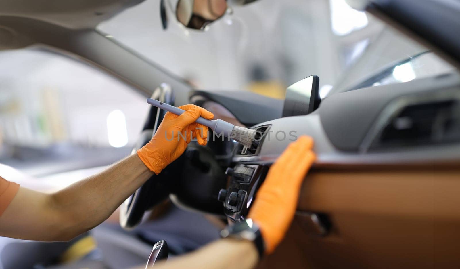 Male repairman cleaning air duct of car with brush closeup. Dry cleaning of car interior concept