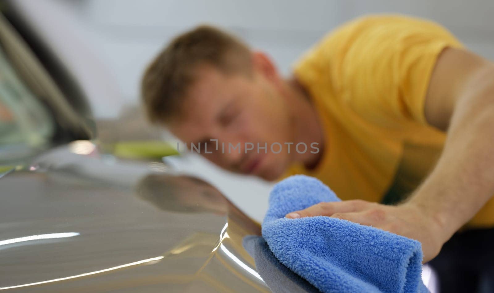 Repairman wiping hood of car with microfiber cloth closeup. Professional car service concept