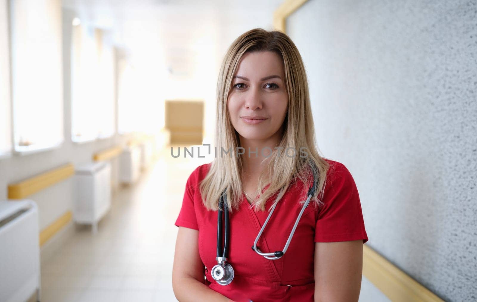 Portrait of young female doctor in red uniform in clinic. Health care concept
