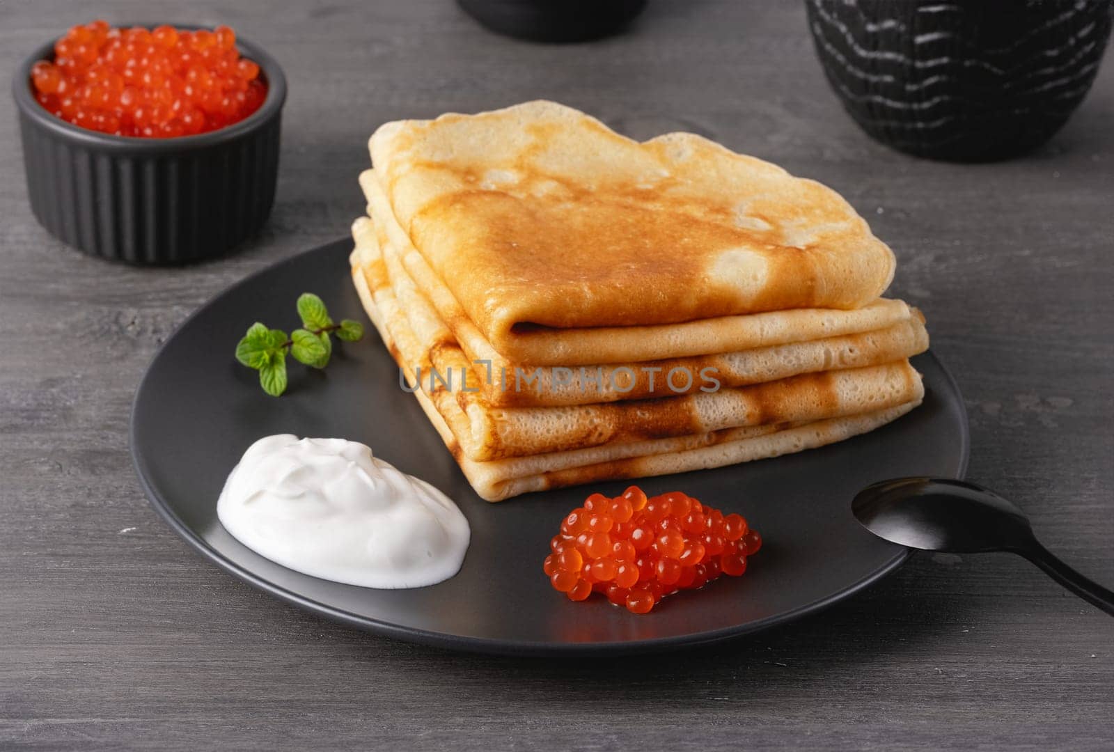 Pancakes with red caviar. Close-up of pancakes stacked on grey background..