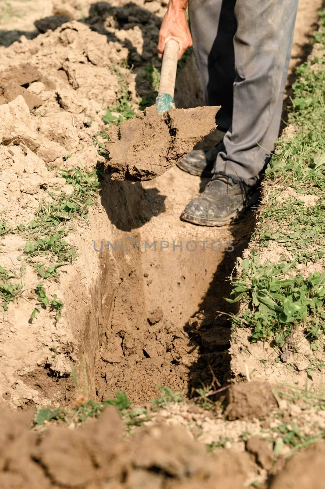 A man shovels a trench for drainage and sewage, close up.