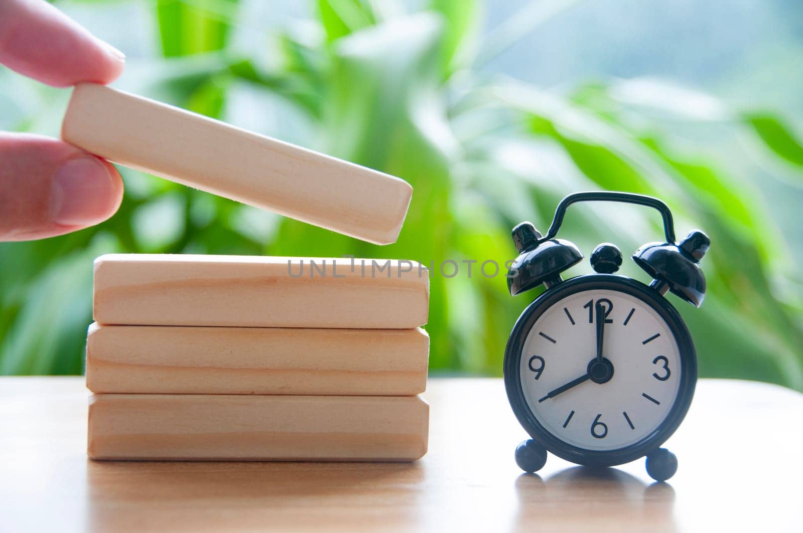 Table alarm clock pointing at 8 am with wooden blocks with customizable space for text. Time concept