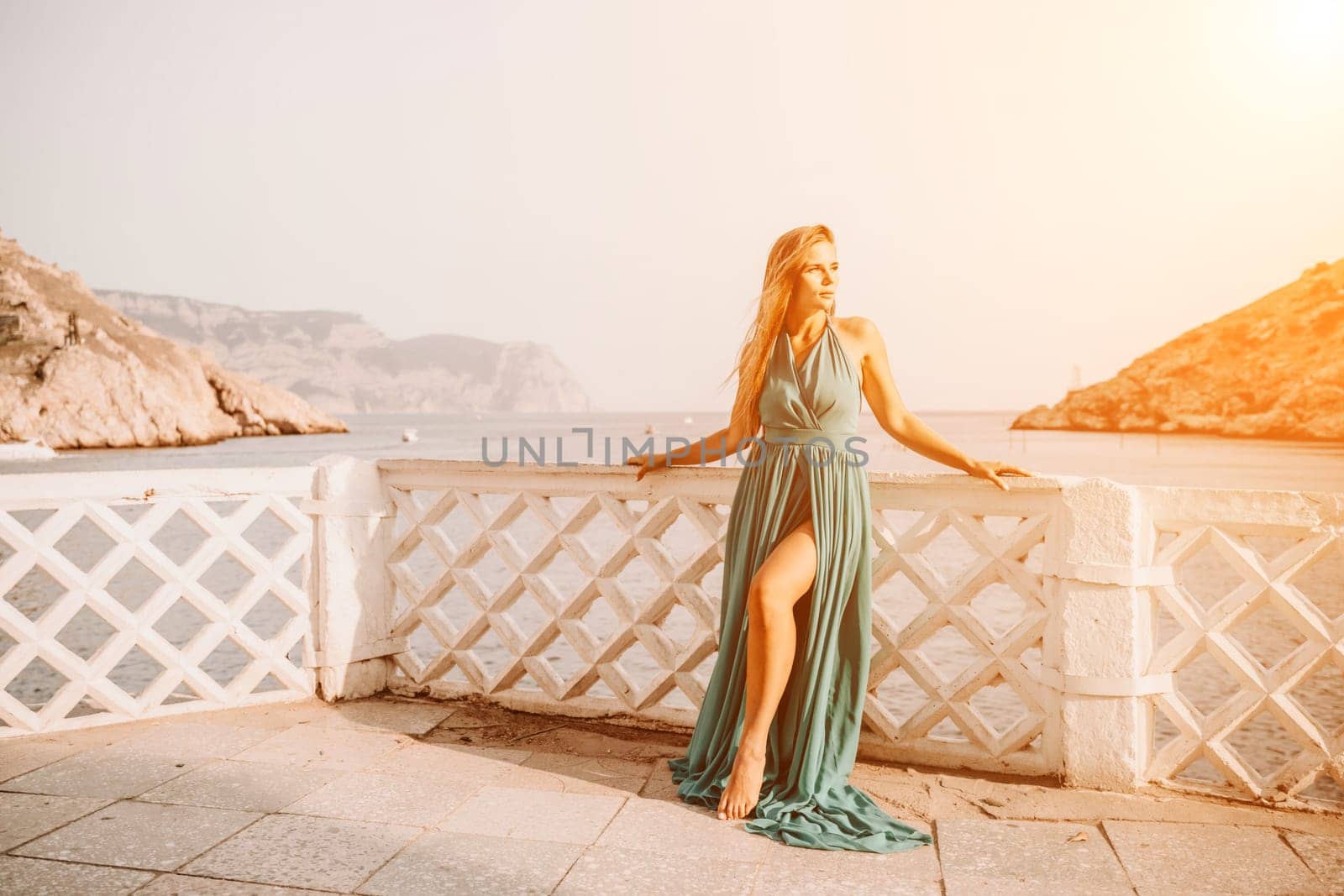 Woman sea trevel green dress. Side view a happy woman with long hair in a long mint dress posing on a beach with calm sea bokeh lights on sunny day. Girl on the nature on blue sky background