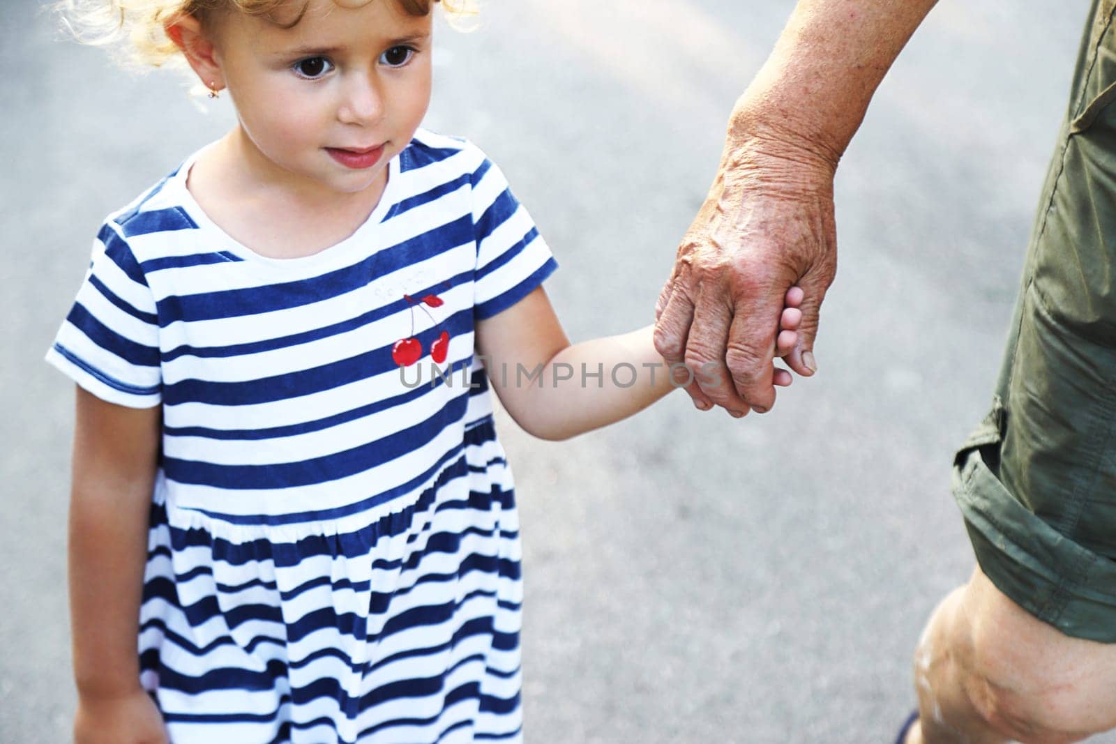 Child with grandmother holding hand. Selective focus. Nature.