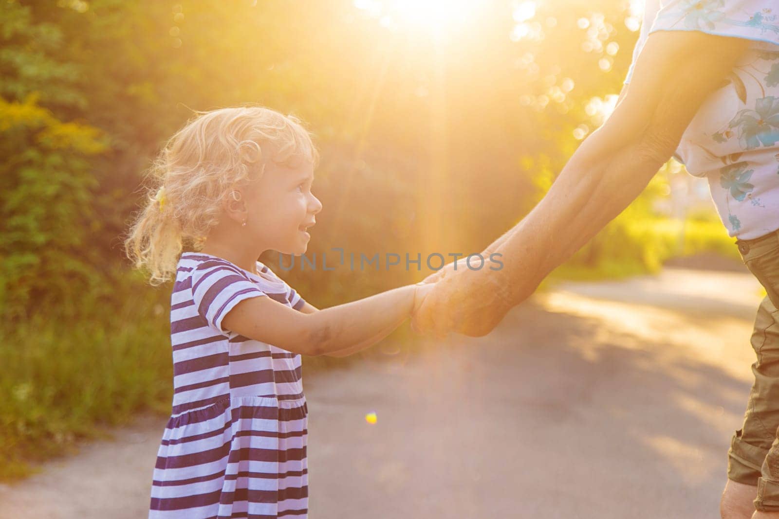 Child with grandmother holding hand. Selective focus. Nature.