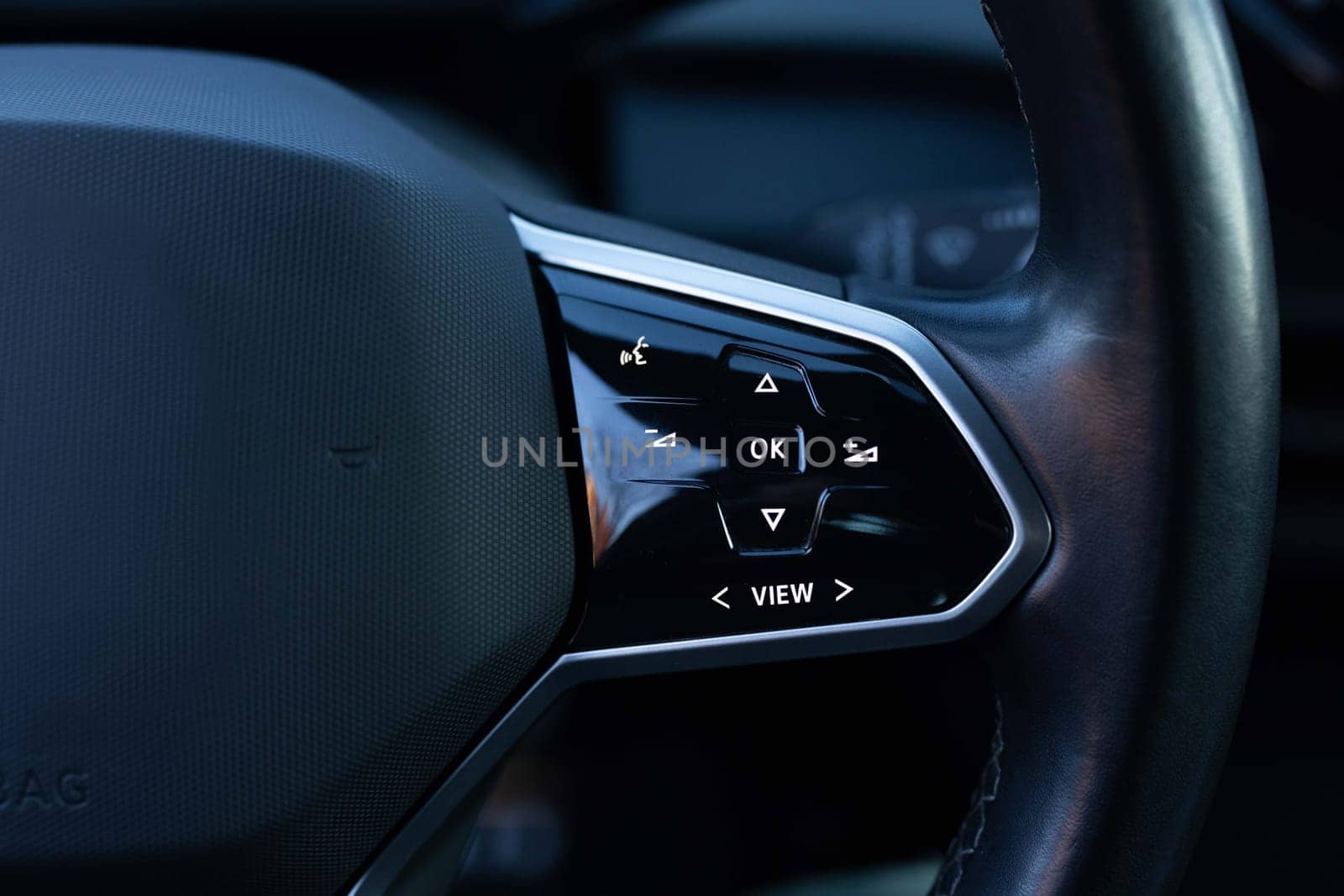 Close-up view of car interior. View of steering wheel of car control music. Volume button of car radio on steering wheel. Turns up the volume of the music in the car