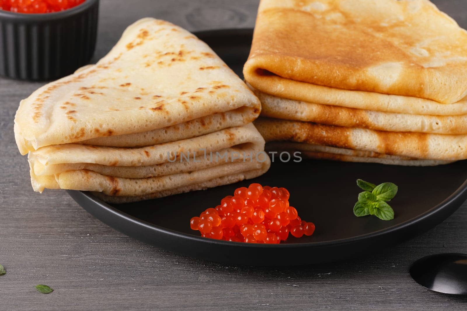 Pancakes with red caviar. Close-up of pancakes stacked on grey background.