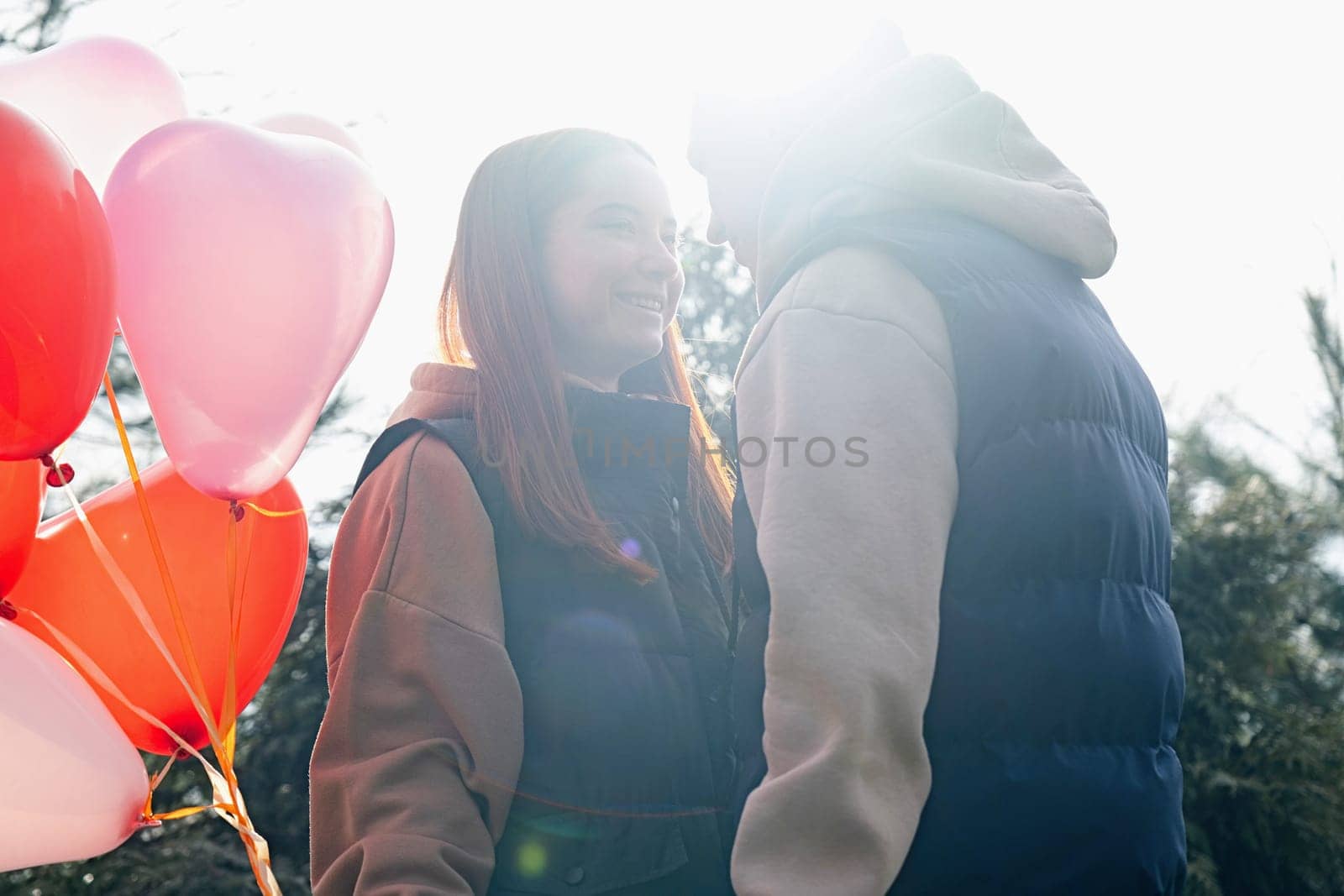 Outdoor photo of happy young woman enjoying date. cheerful romantic couple dating outdoors with balloons, backlit