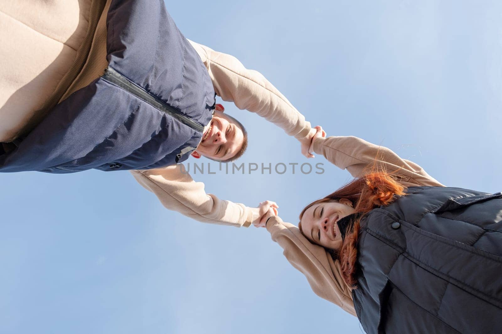 Outdoor photo of happy young woman enjoying date. cheerful romantic couple dating and holding hands outdoors, sky background