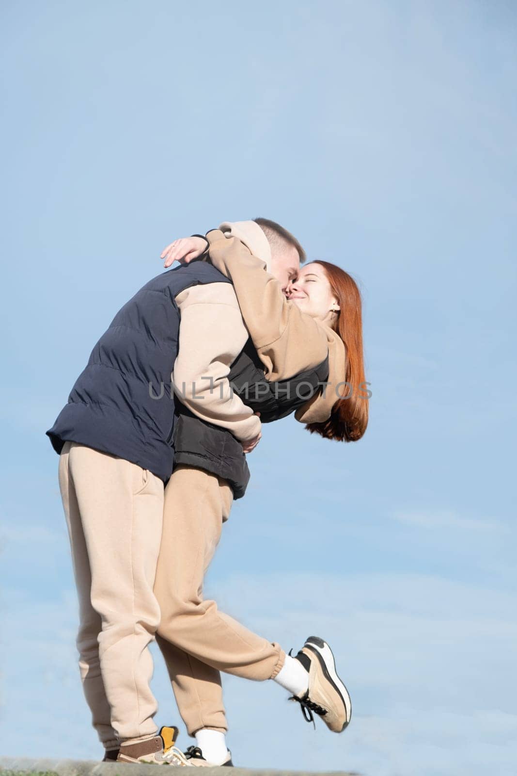 Outdoor photo of happy young woman enjoying date. cheerful romantic couple dating and hugging outdoors, sky background