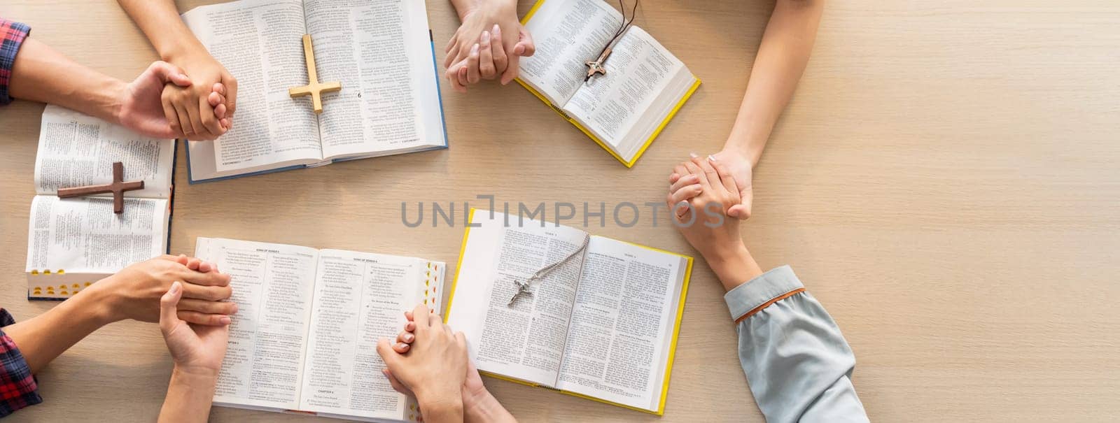 Cropped image of group of people praying together while holding hand on holy bible book at wooden church. Concept of hope, religion, faith, christianity and god blessing. Top view. Burgeoning.