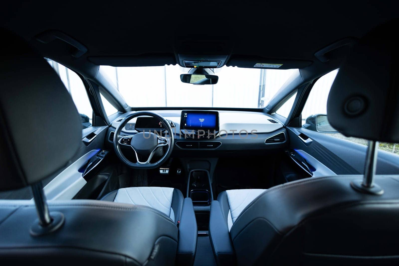 Electric car interior details adjustments. Inside car interior with front seats, driver and passenger, textile, multimedia, windows, console, gear shift, electric buttons, digital speedometer.