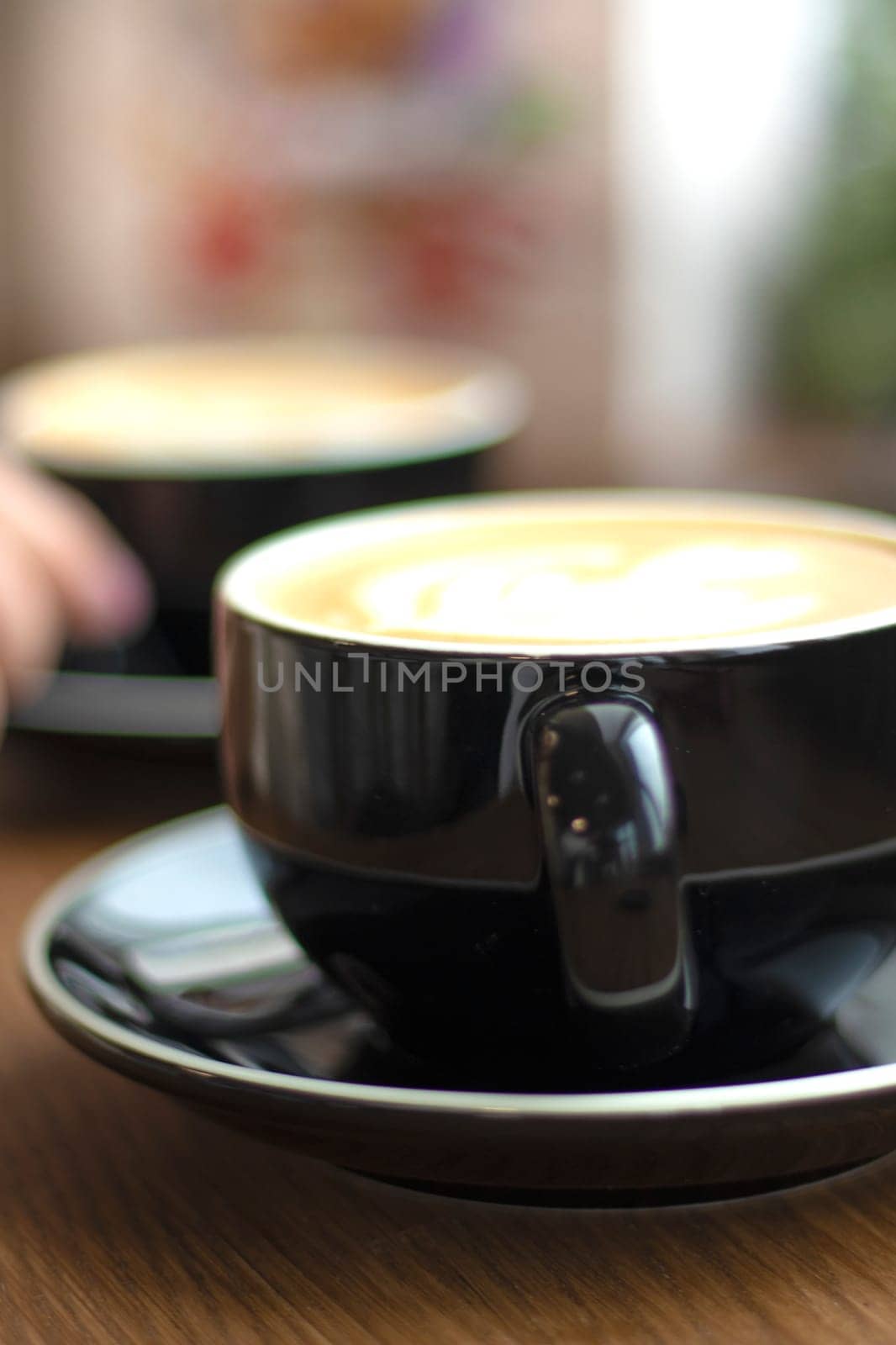 selective focus. Two cups of cappuccino with latte art on wooden background. Beautiful foam, greenery ceramic cups, stylish toning, Fresh cups espresso coffee with milkon black background.