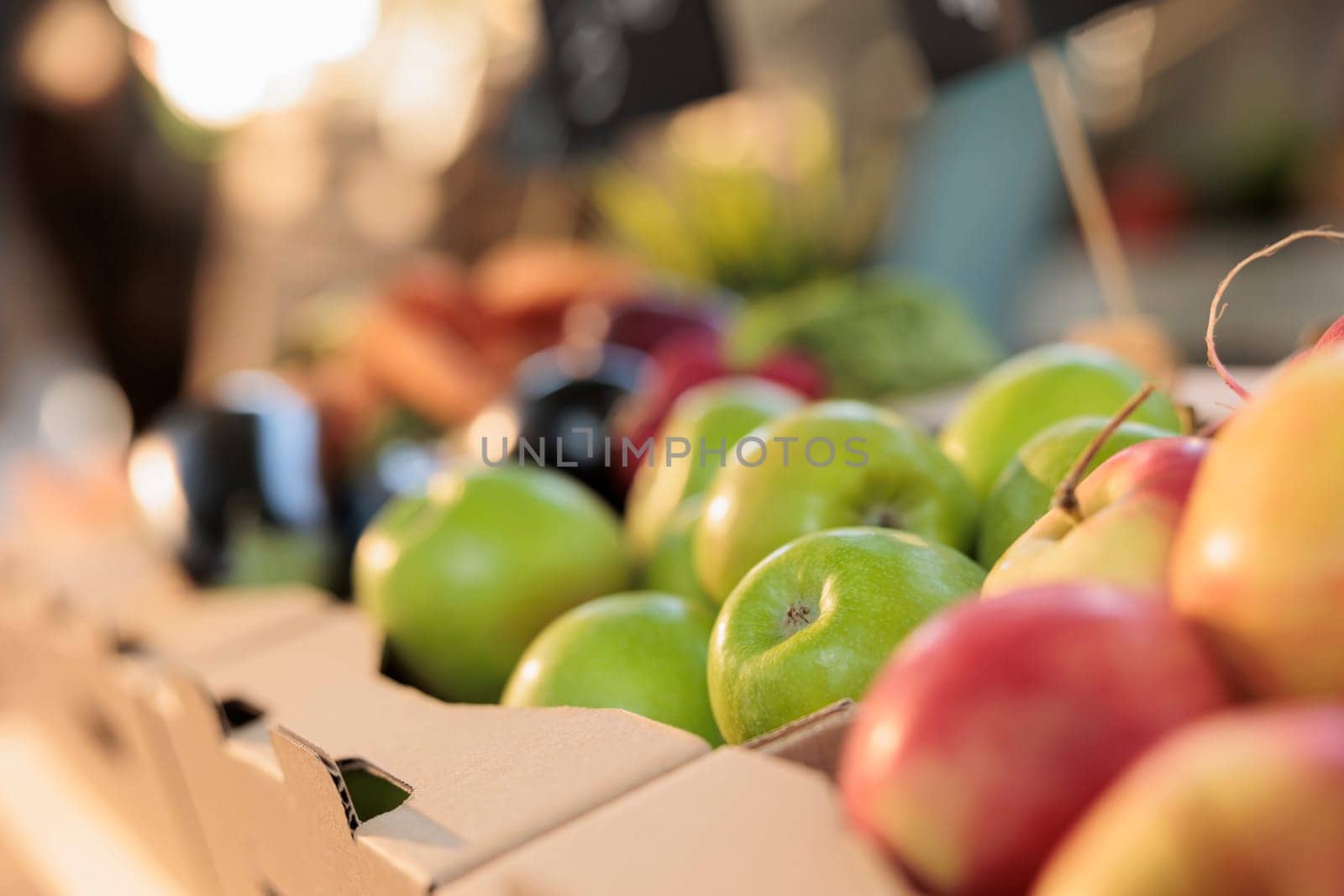 Natural organic food and health. Close up of fresh ripe green apples at farmers market, selective focus. Cardboard boxes full of various local seasonal fruits and vegetables on greenmarket stall