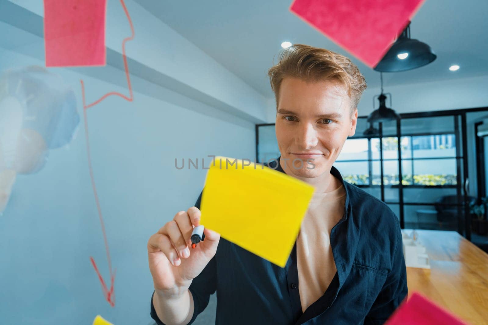 Professional caucasian businessman writing marketing idea by using mind map and sticky notes on glass board at modern meeting room. Creative business and planing concept. Closeup. Immaculate.