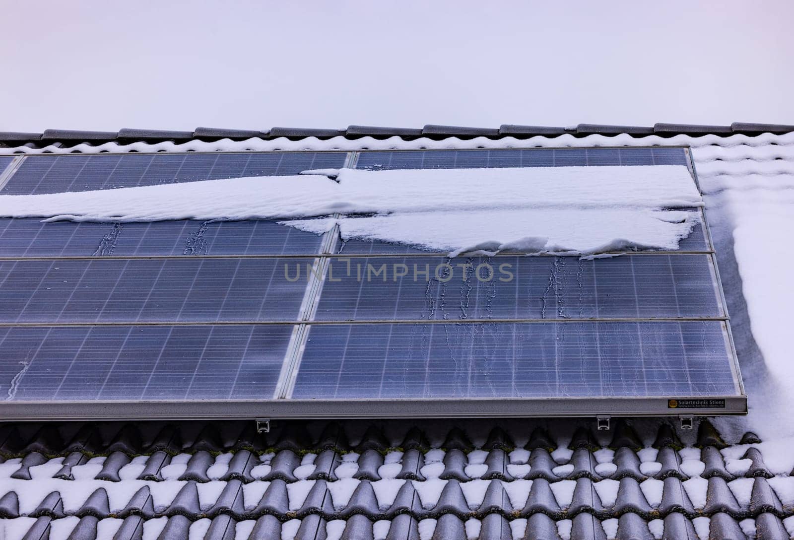 Snow-covered PV system on a private rooftop by astrosoft