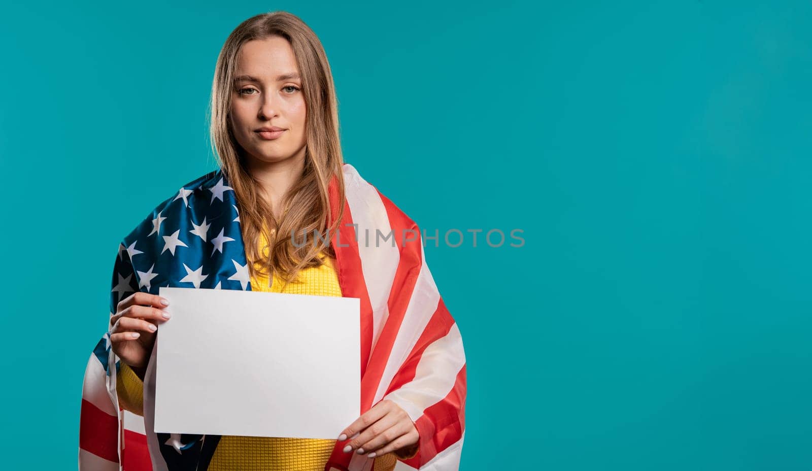 American woman with white a4 paper poster. Copy space. Smiling lady, blue studio. High quality photo