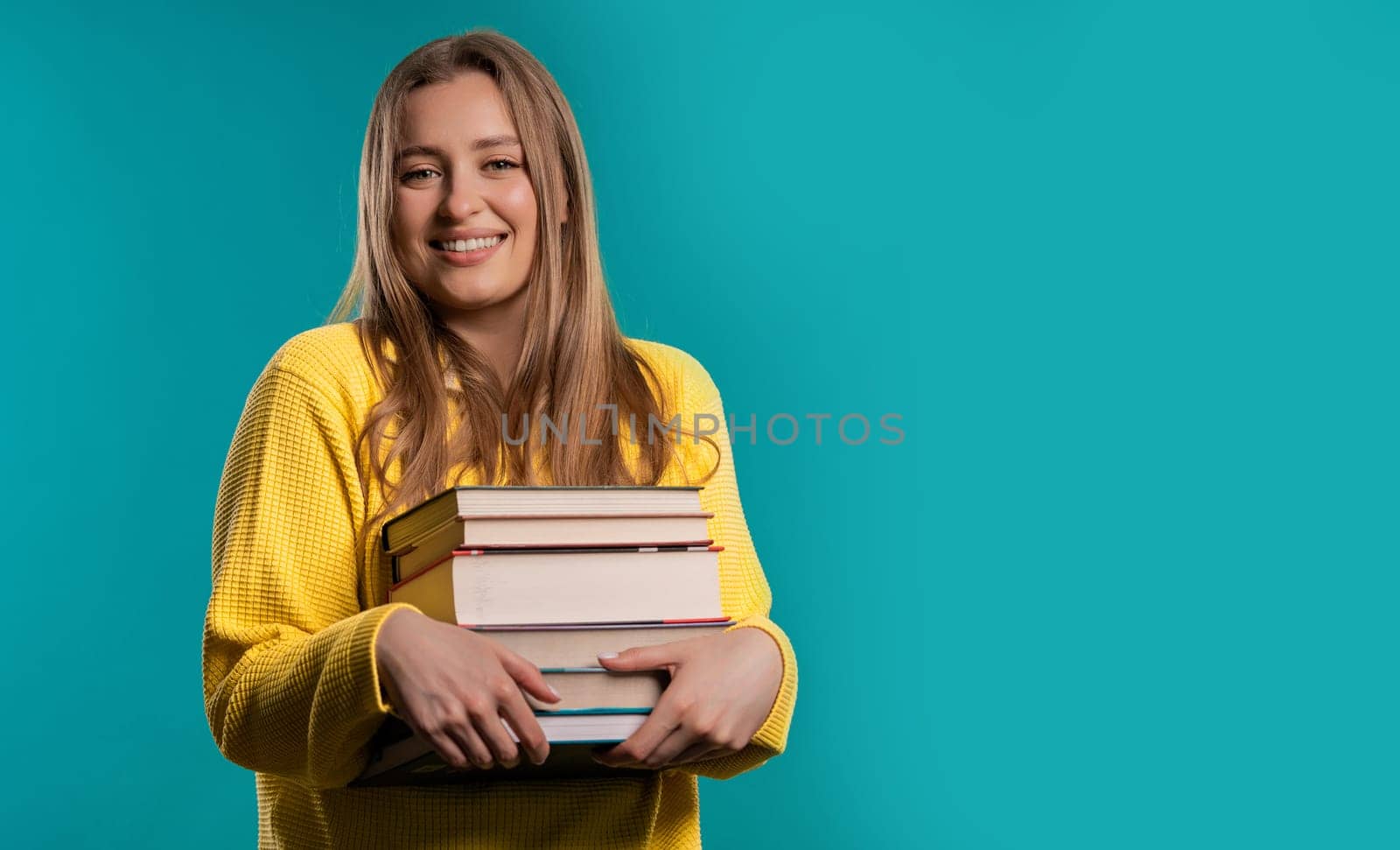 Happy student woman with stack books from library, blue background. Copy space by kristina_kokhanova