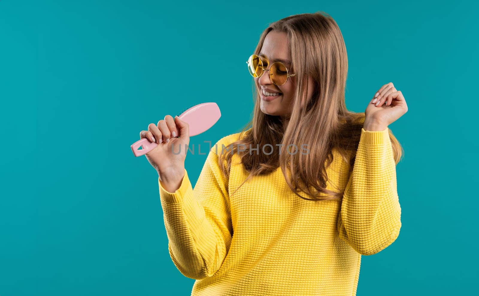 Woman singing, dancing with hair brush instead microphone on blue background by kristina_kokhanova