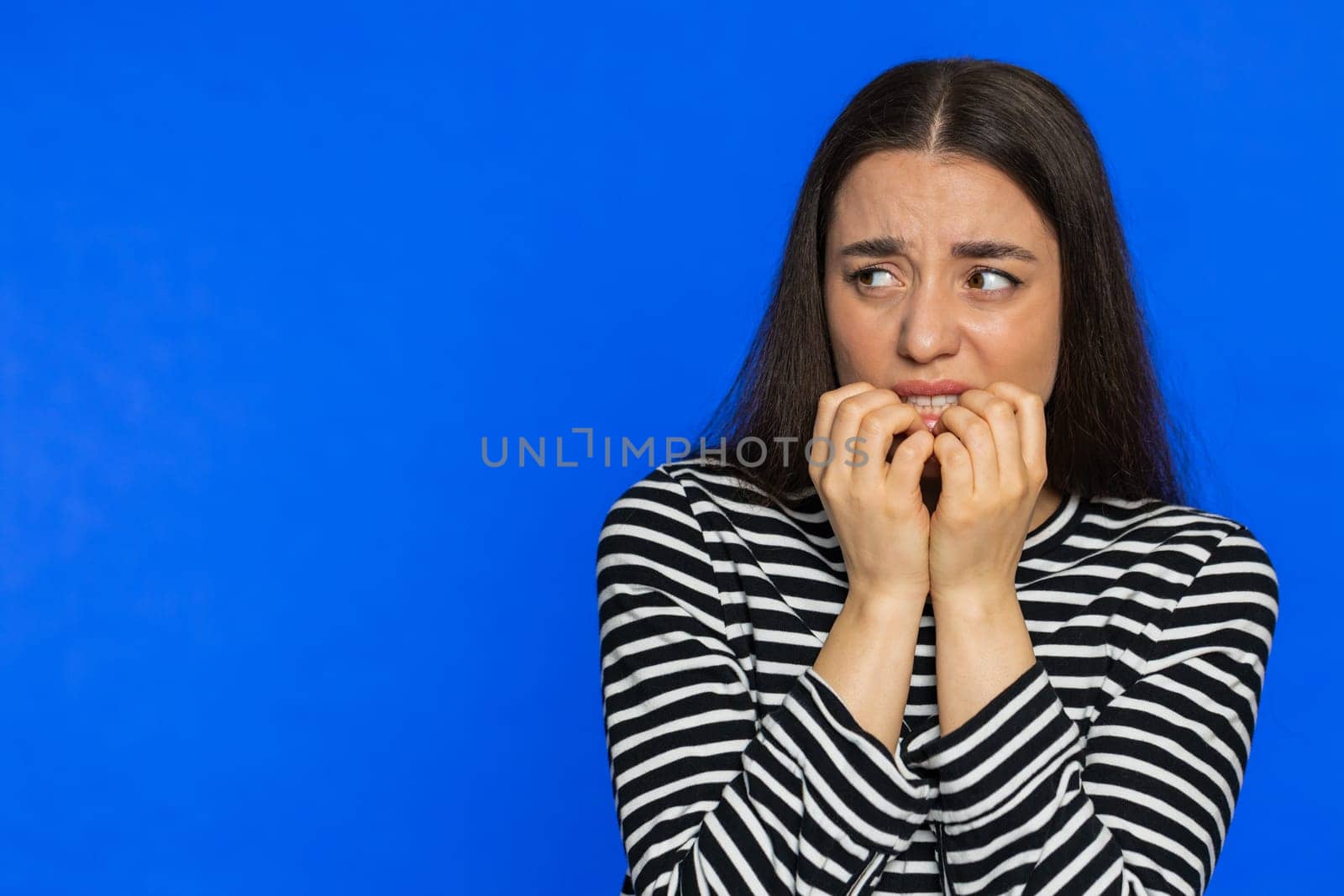 Scared stressed woman terrified about danger problems, suffering phobia anxiety disorder expresses fear waving no insecure stress panic. Depressed fearful girl on blue studio background. Copy-space