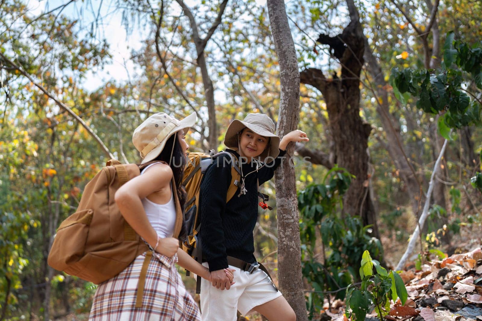 Happy LGBT Lesbian couple Travelers Hiking with Backpacks in forest Trail. LGBT Lesbian Couple Hikers with backpacks walks in mountains in vacation.