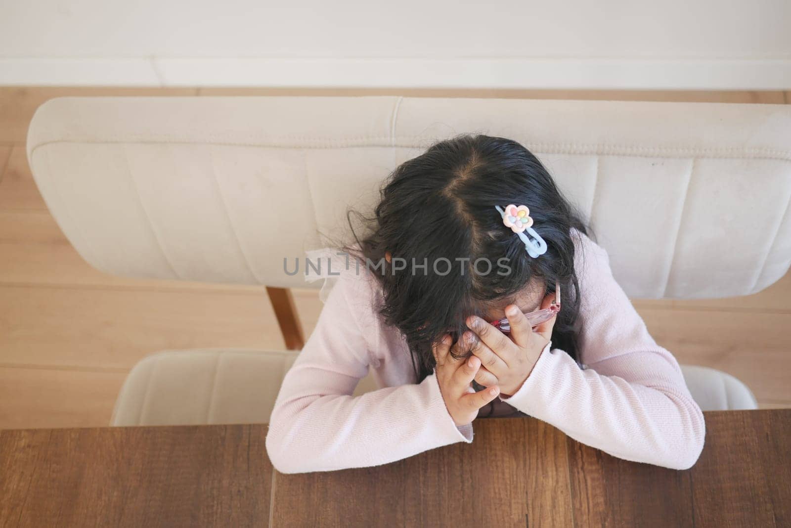 a upset child girl cover her face with hand .