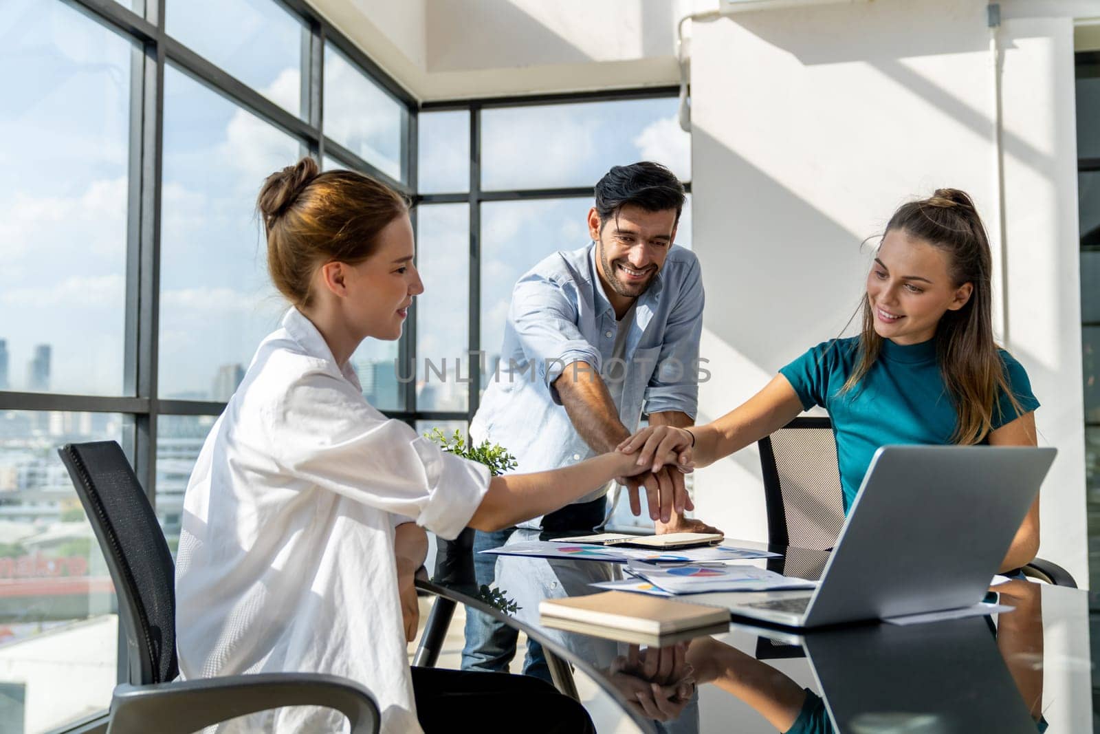 Group of skilled businesspeople putting hands together at modern office.Happy smart business team working together. Represented unity, love, team, working together, partnership, work place. Tracery.