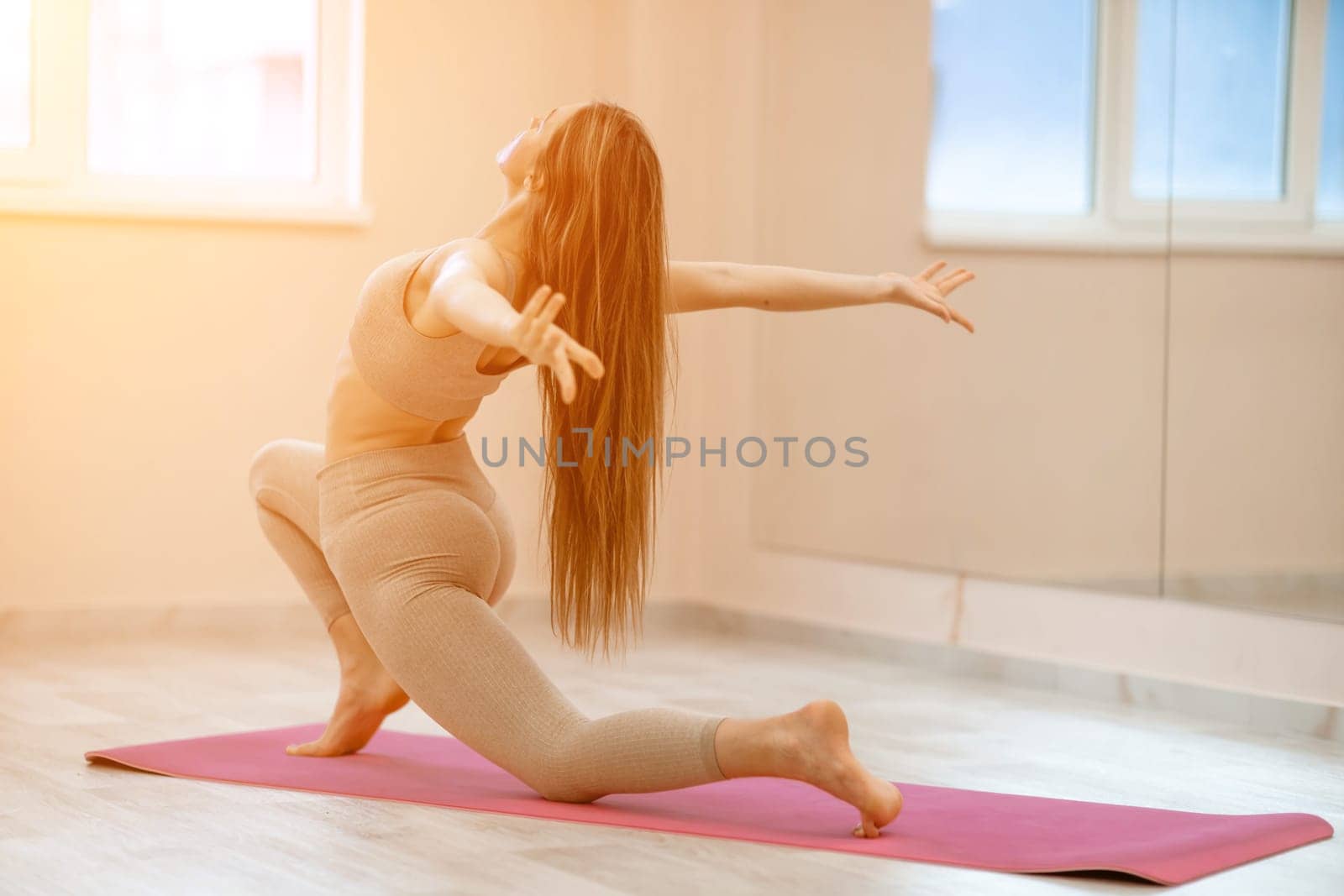 Girl does yoga. Young woman practices asanas on a beige one ton background. by Matiunina